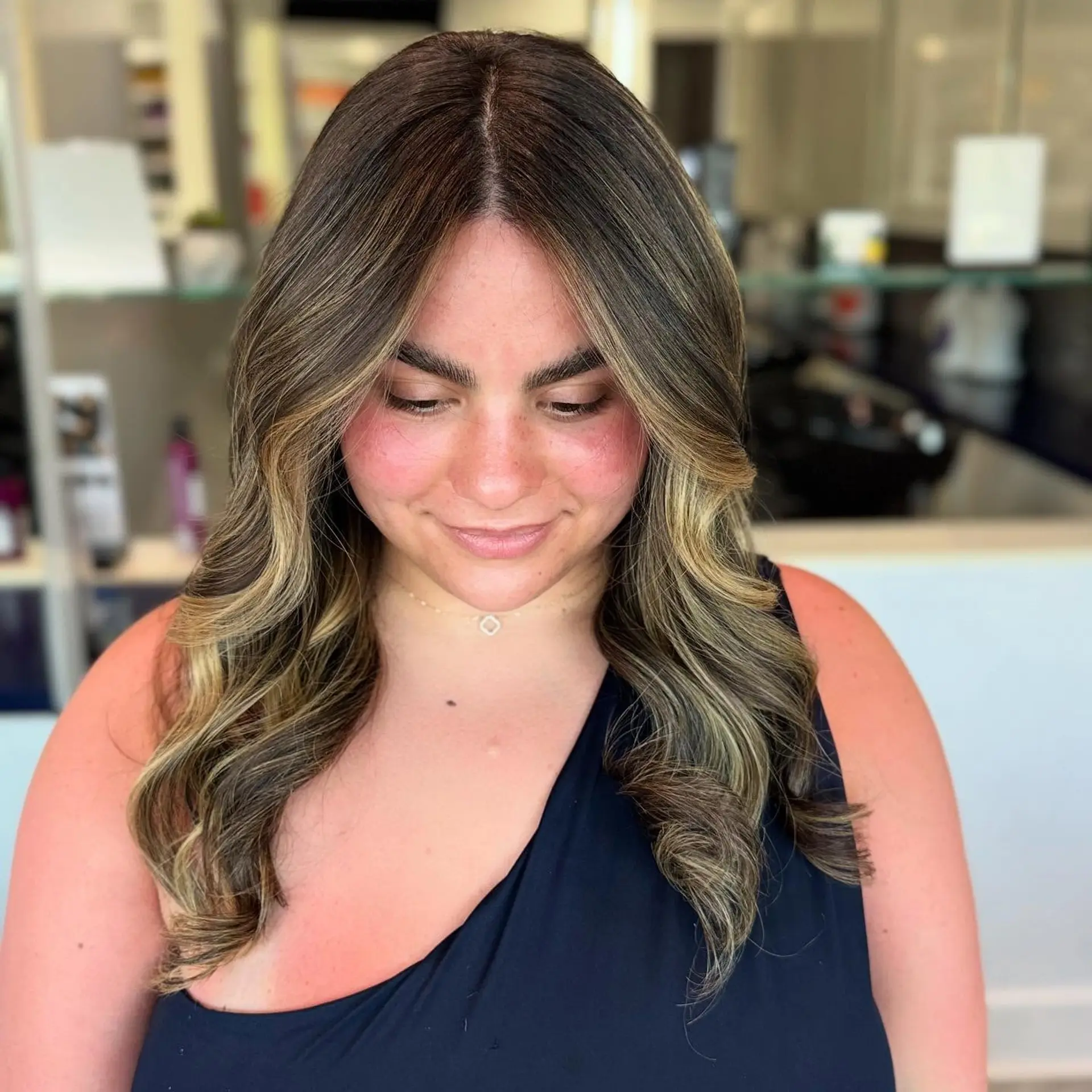 A medium-length wavy hairstyle with a bronzed blonde balayage. 3
