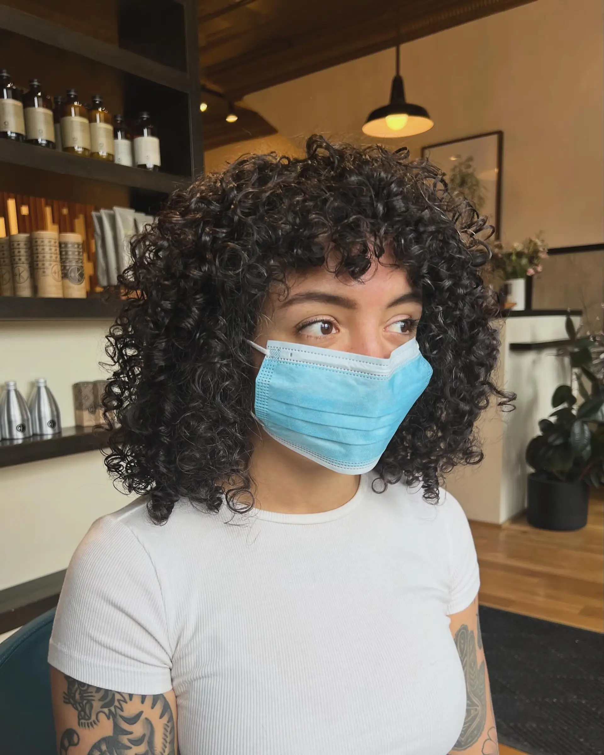 A medium-length curly shag haircut with face-framing curly bangs. 1