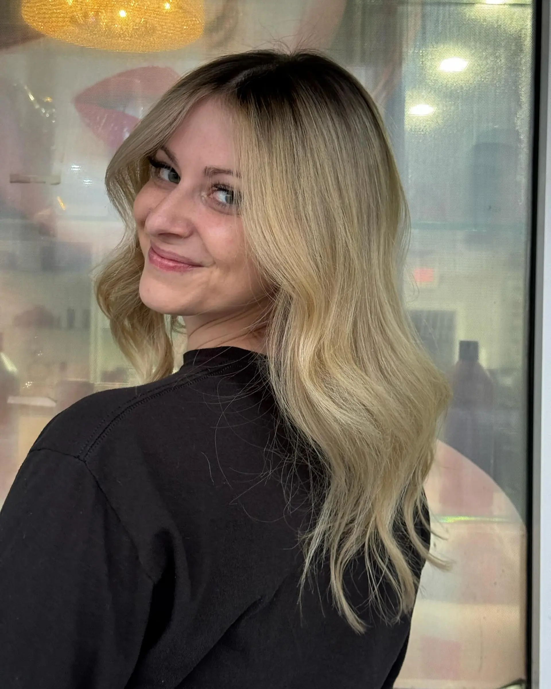 Long, wavy hair with a dark root ombre to blonde beach waves. 3