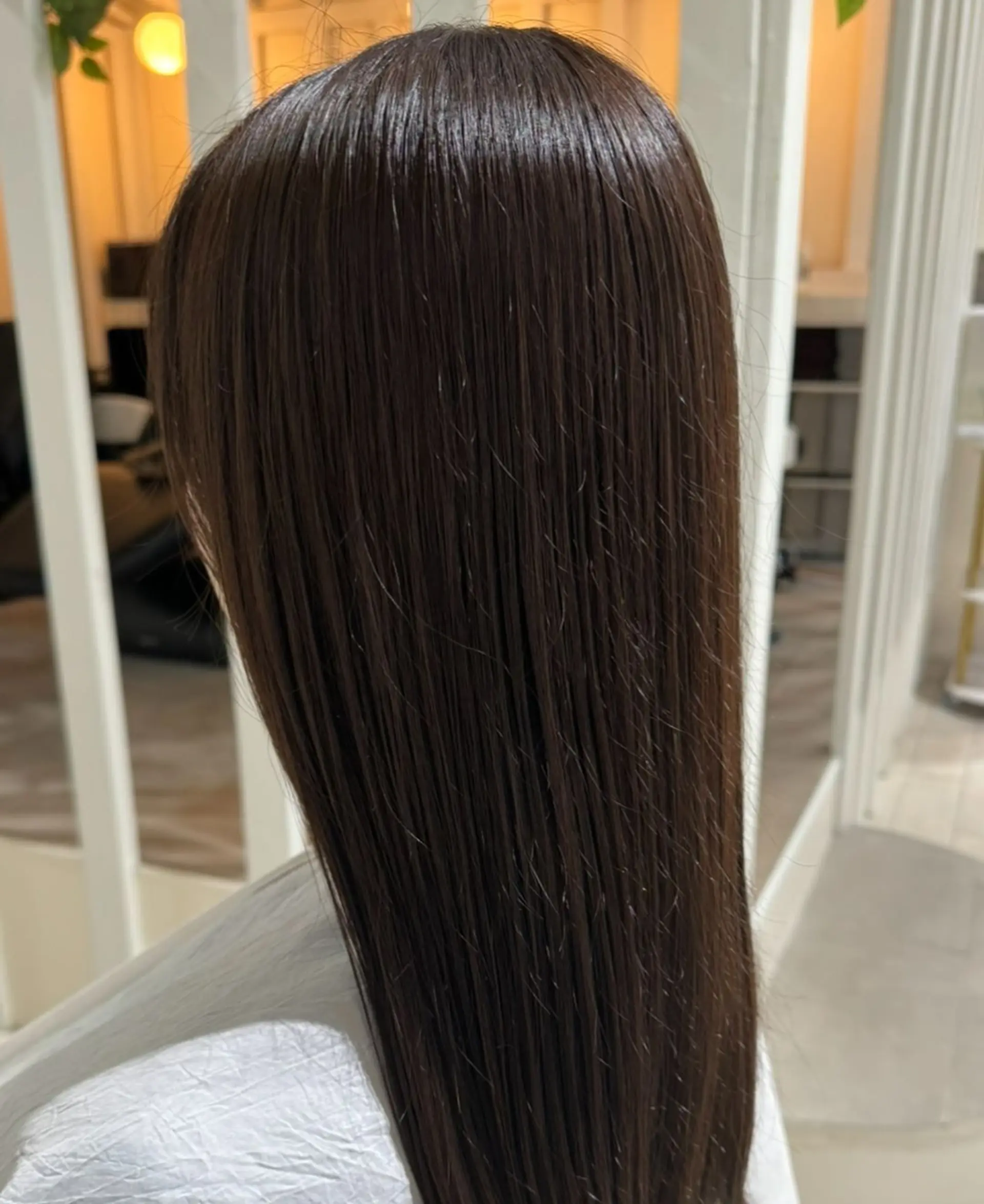 Long, dark brown straight hair with a glossy finish, minimal layers, and a pin-straight texture, creating a sleek and polished look. 1