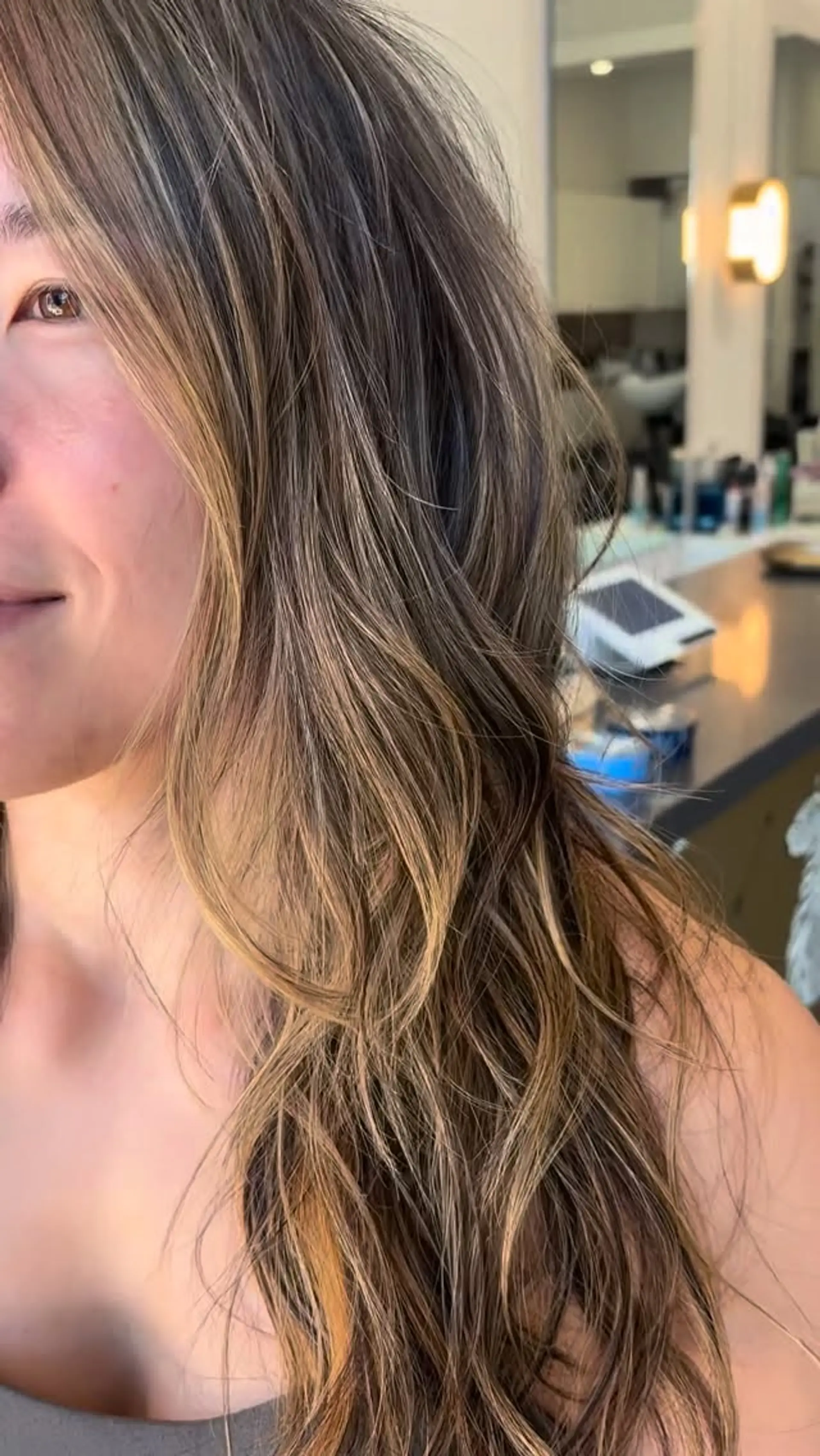Long dimensional bronde hair featuring soft, face-framing warm blonde highlights blended into a brunette base with gentle, textured waves. 1