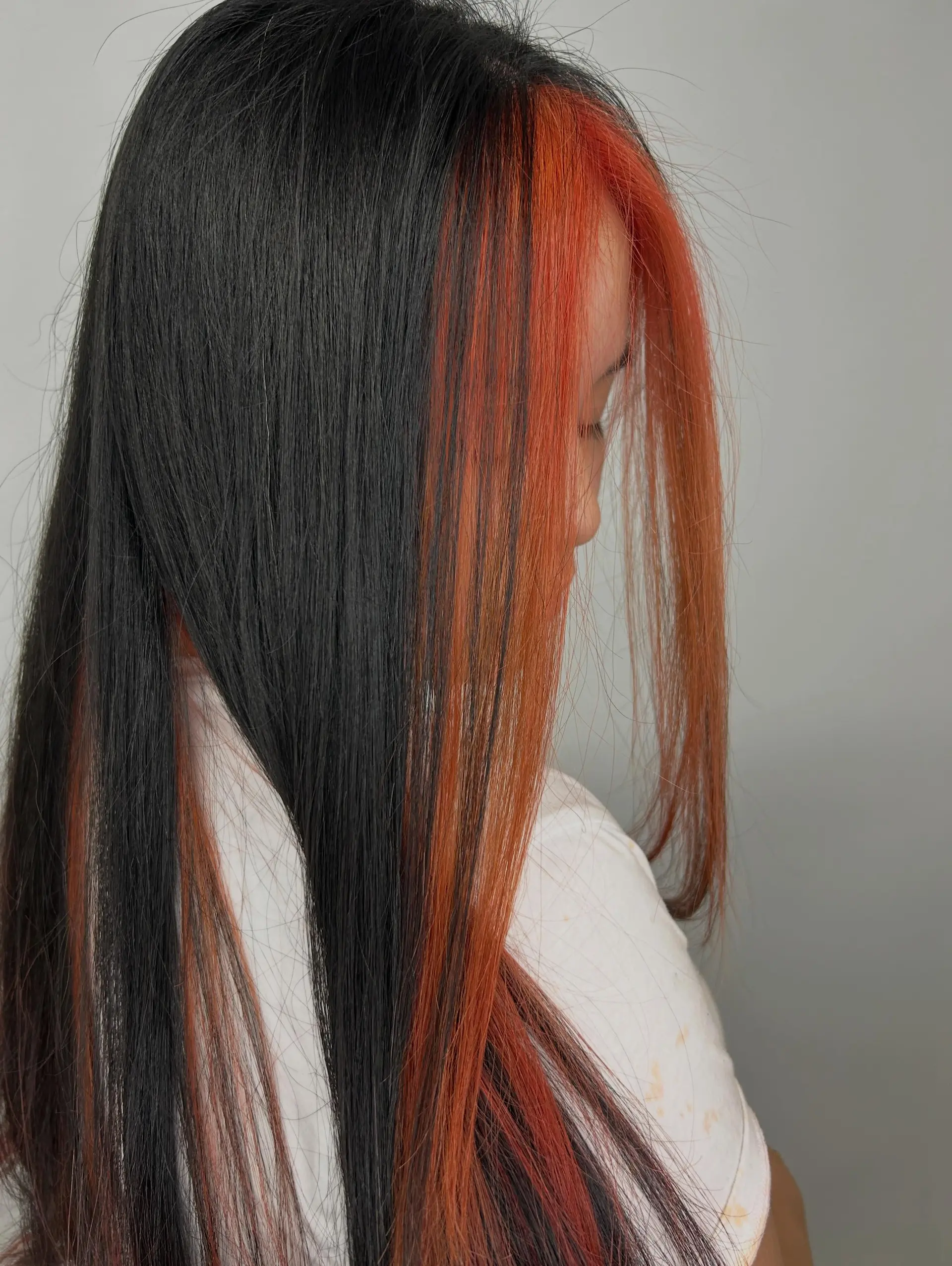 Long straight black hair featuring a vibrant copper-orange peek-a-boo section framing the face. 1