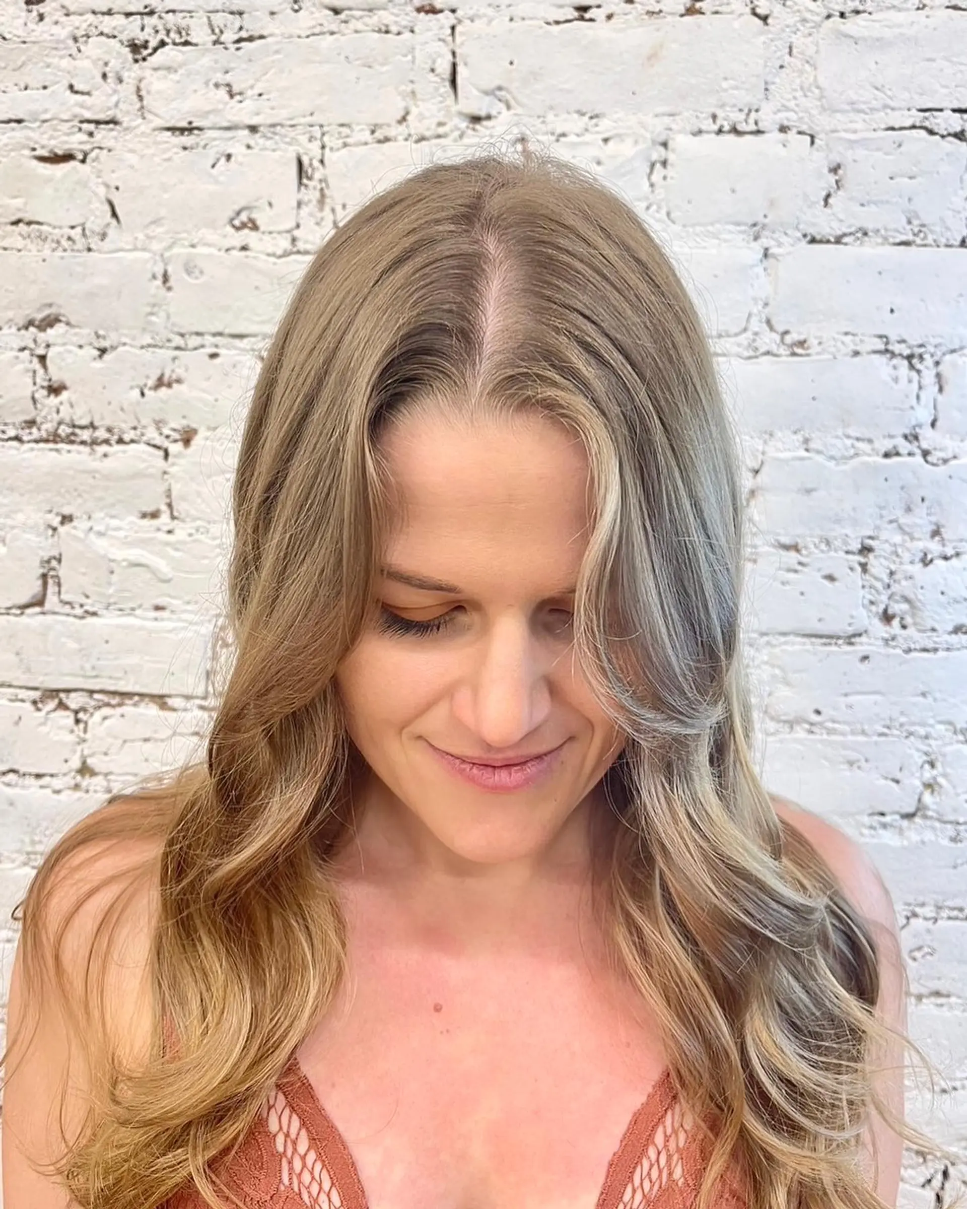 Long cascading waves featuring blended ash blonde highlights and soft face-framing layers. 1