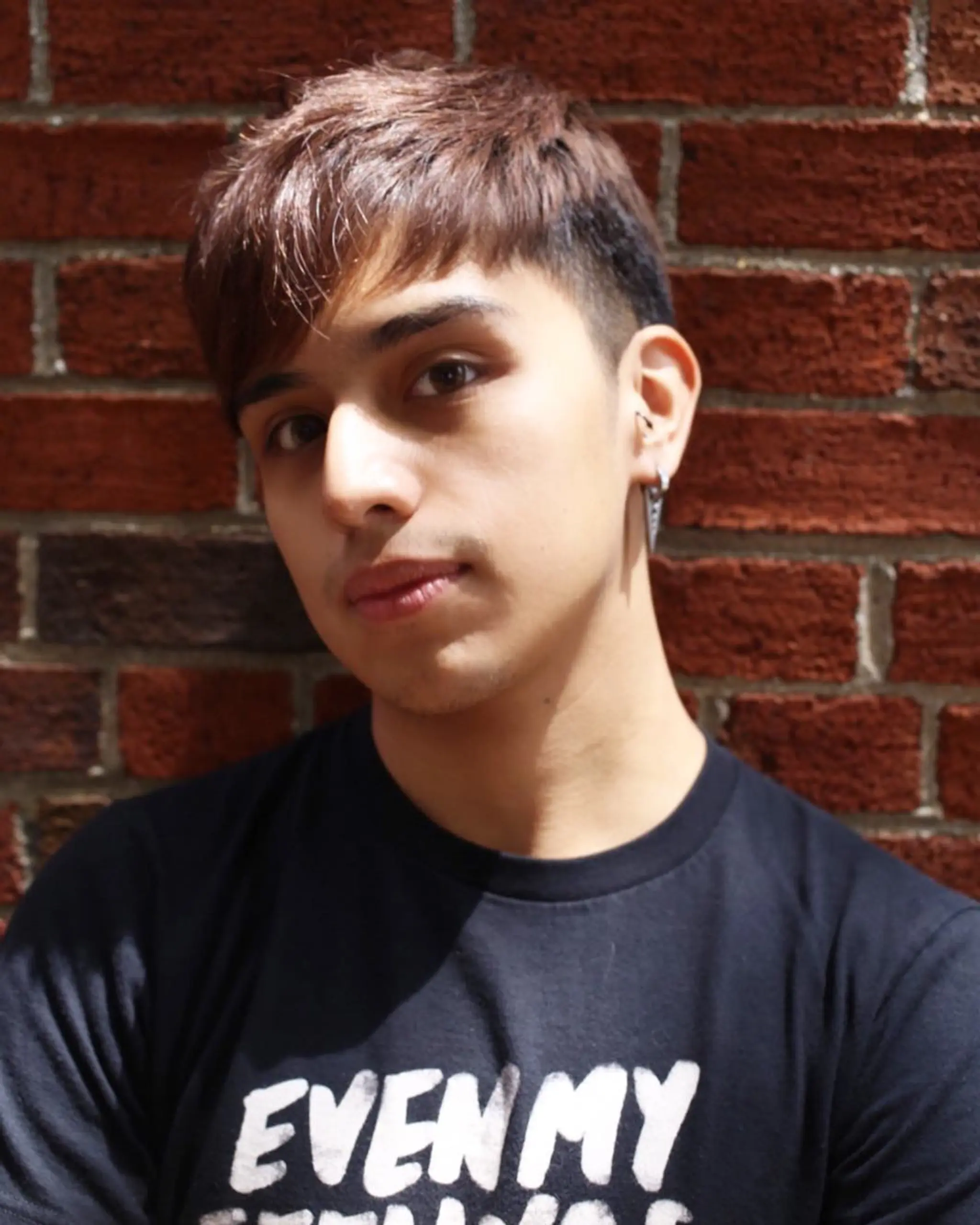 Short, straight hair styled with a textured top and fringe that slightly covers the forehead. The sides are tapered and blend into the longer hair on top, creating a neat undercut look. The hair color is brown.