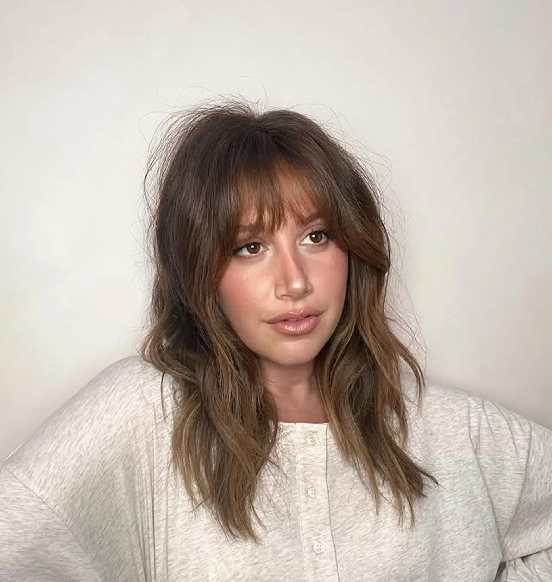 A medium-length shag haircut with face-framing layers and Bardot bangs. 1