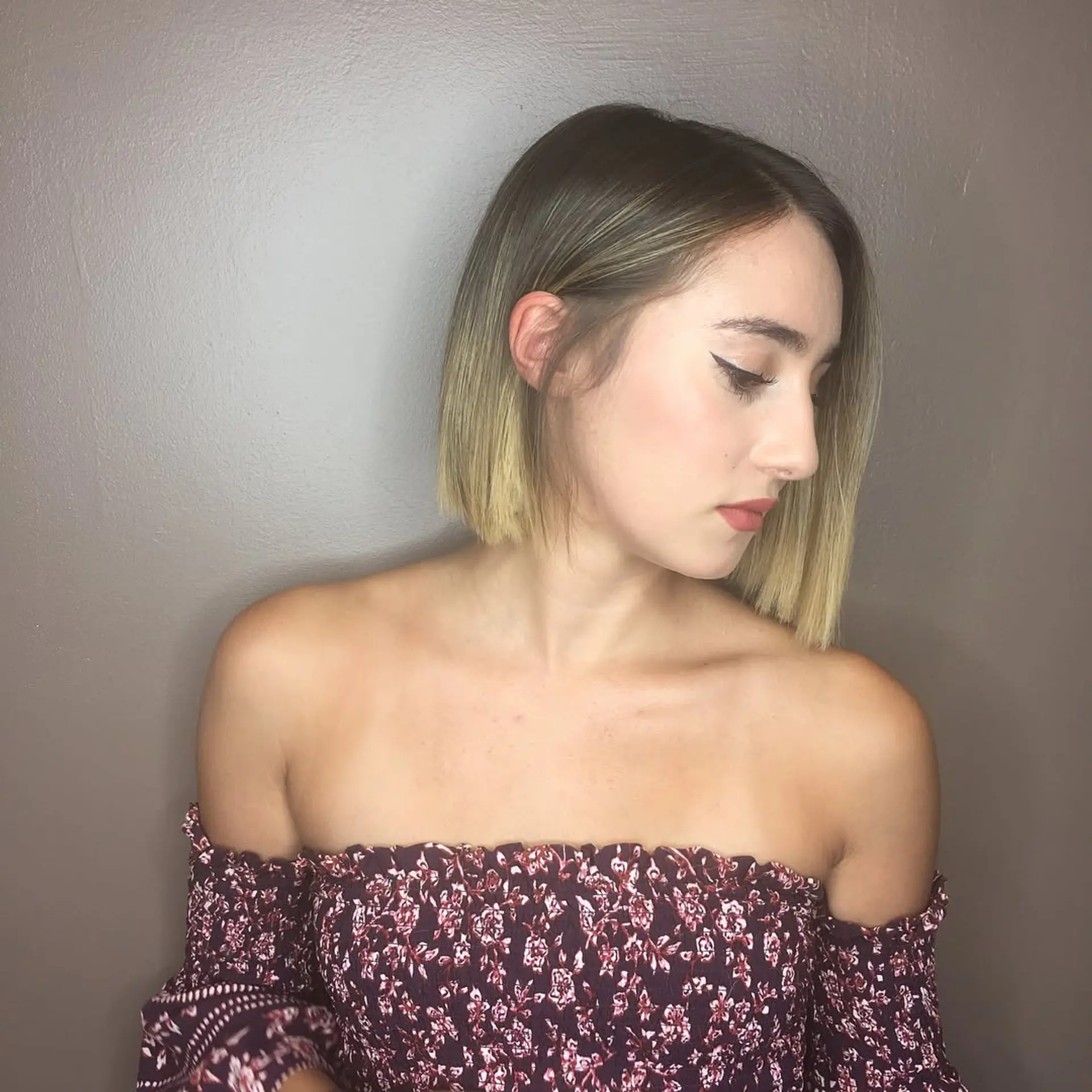 A sleek, chin-grazing blunt bob cut with a side-part and one side tucked behind the ear, featuring dark roots blending into bright blonde balayage ends. 1