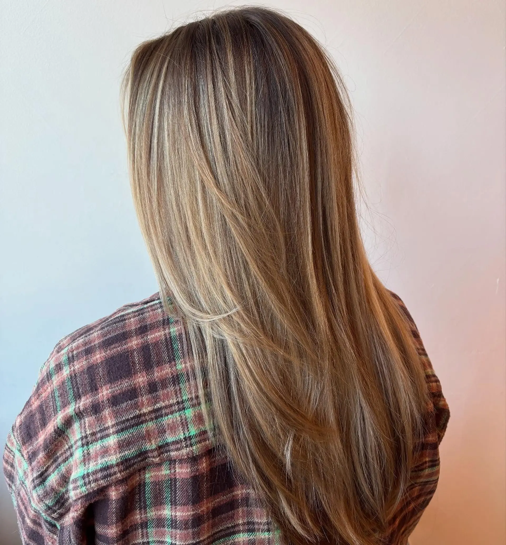 Long, sleek straight hair enhanced with soft dimensional blonde balayage highlights seamlessly blended into a light brown base. 1