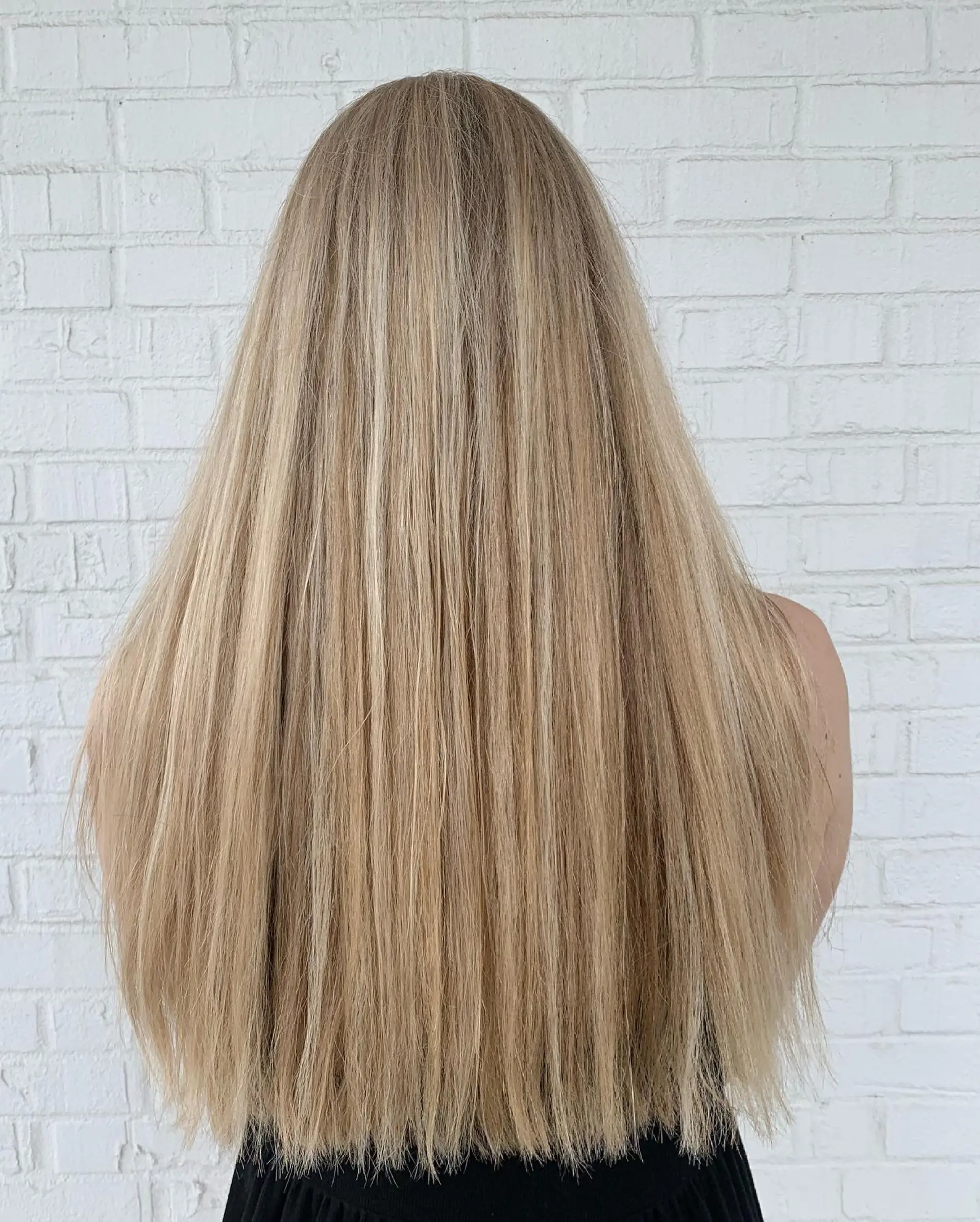 Very long, straight hair featuring a seamless full blonde highlight application for a bright, dimensional finish. 1