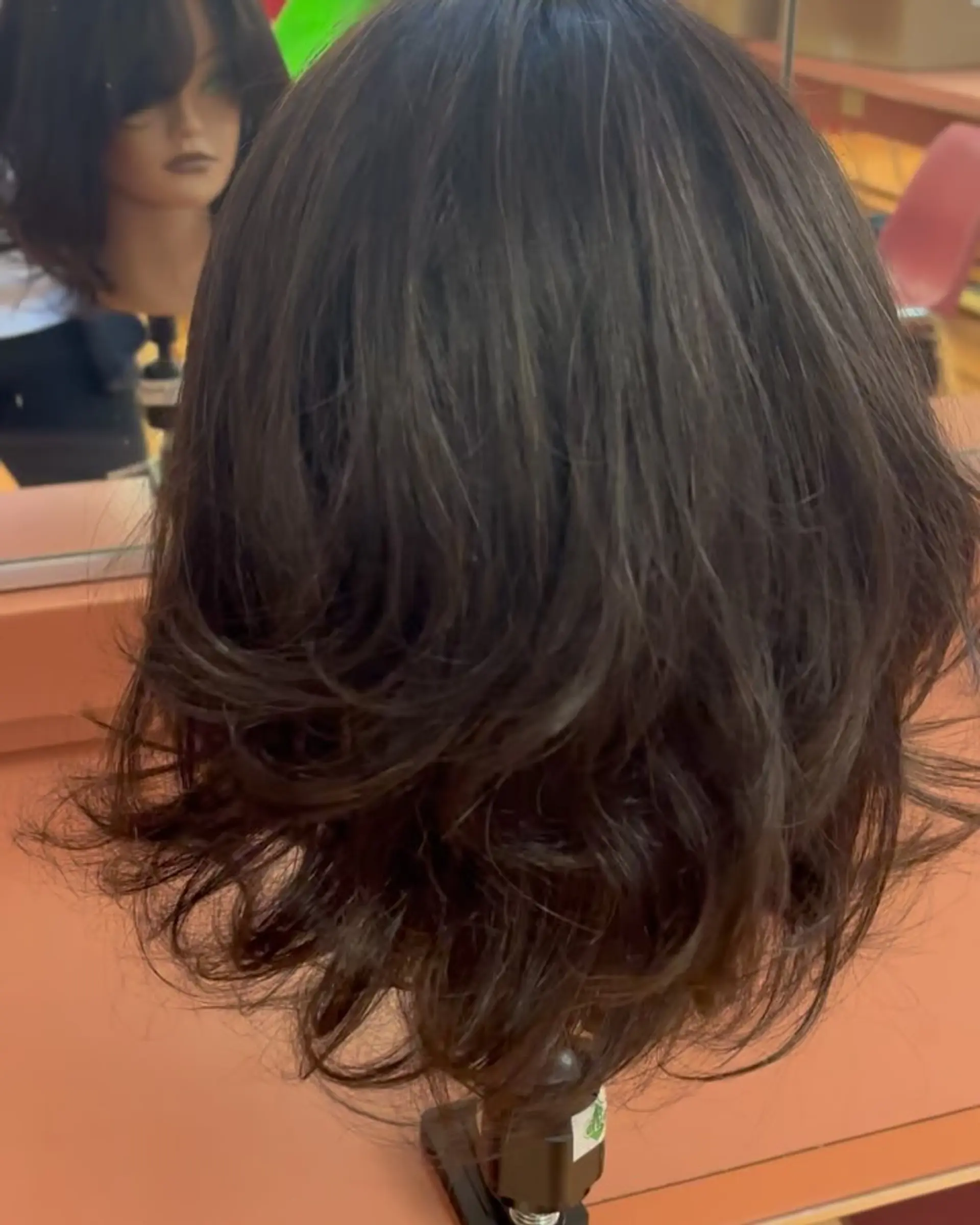 Medium-length dark brown hair styled with soft, flipped layers and natural movement. 1
