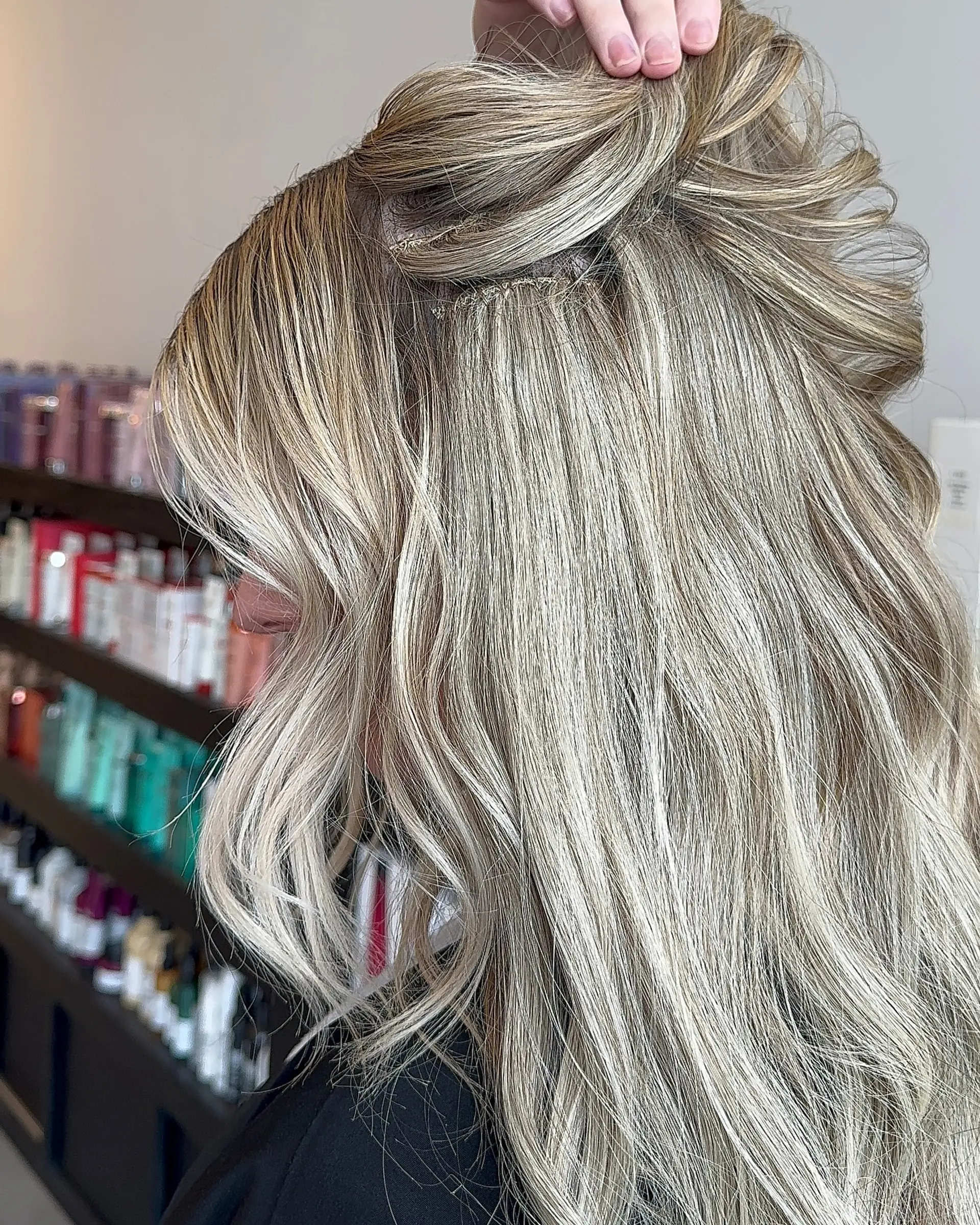 Sewn-in weft hair extensions seamlessly integrated into dimensional cool blonde hair with soft, natural texture. 1