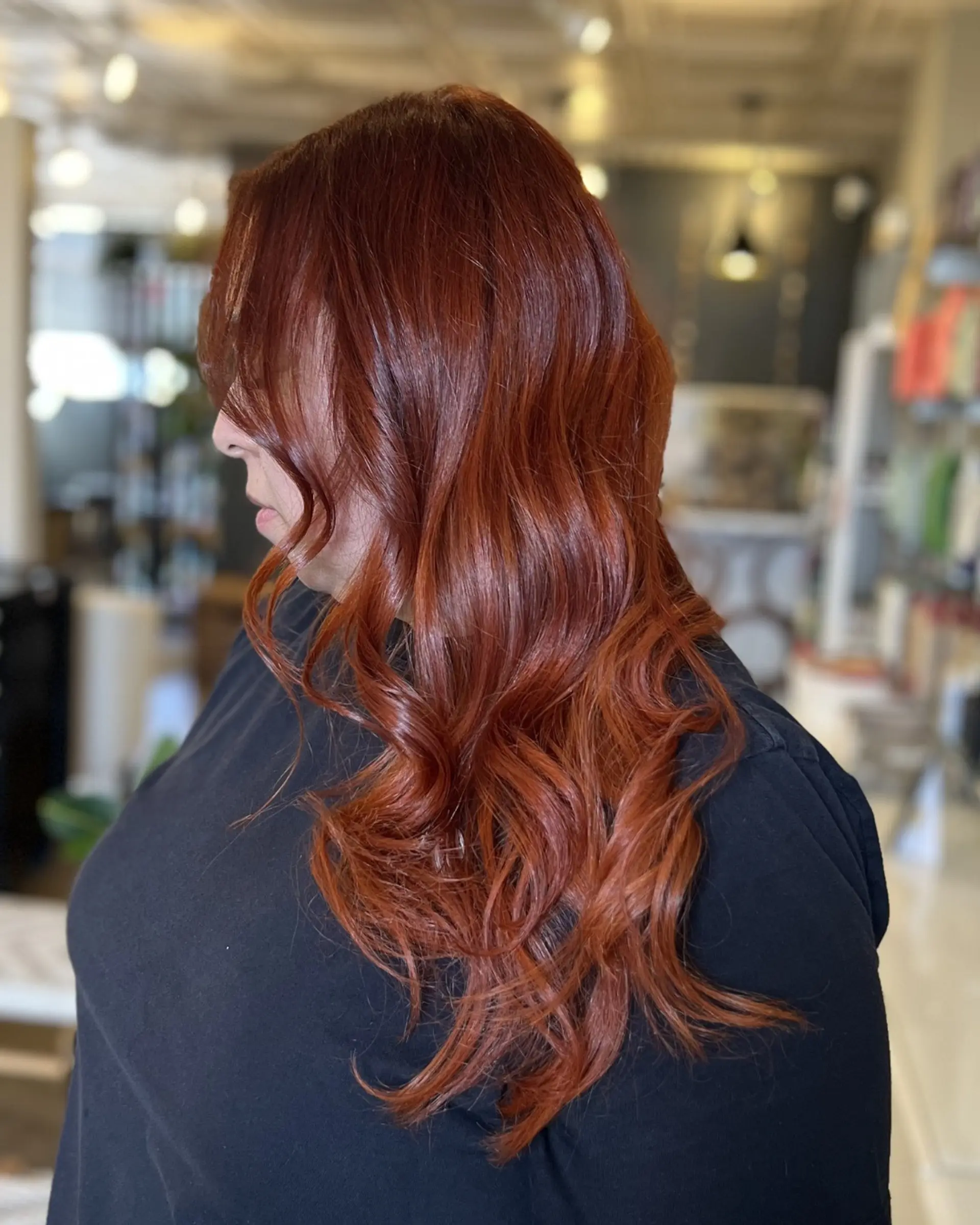 Rich auburn and warm copper balayage finished with glossy, loose waves. 1
