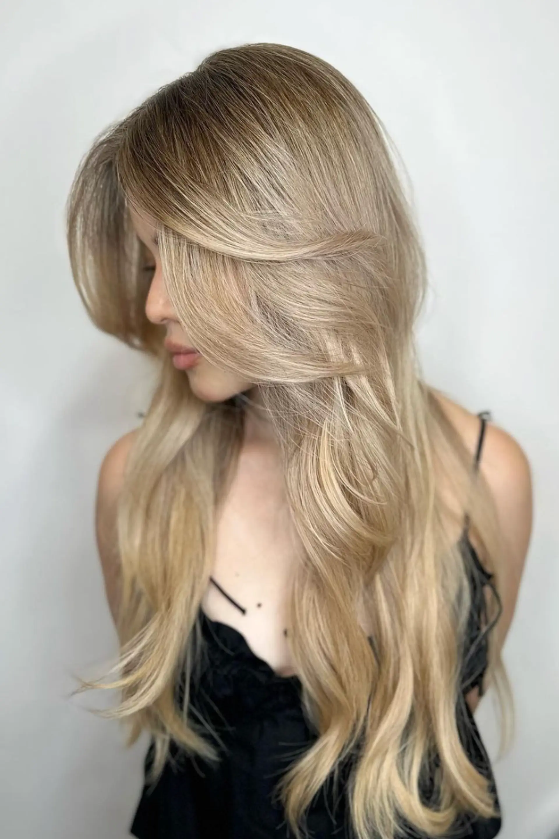 Long, wavy blonde hair with layers and side swept bangs, featuring soft waves and a natural look.

Color by @simabeautynyc
 1