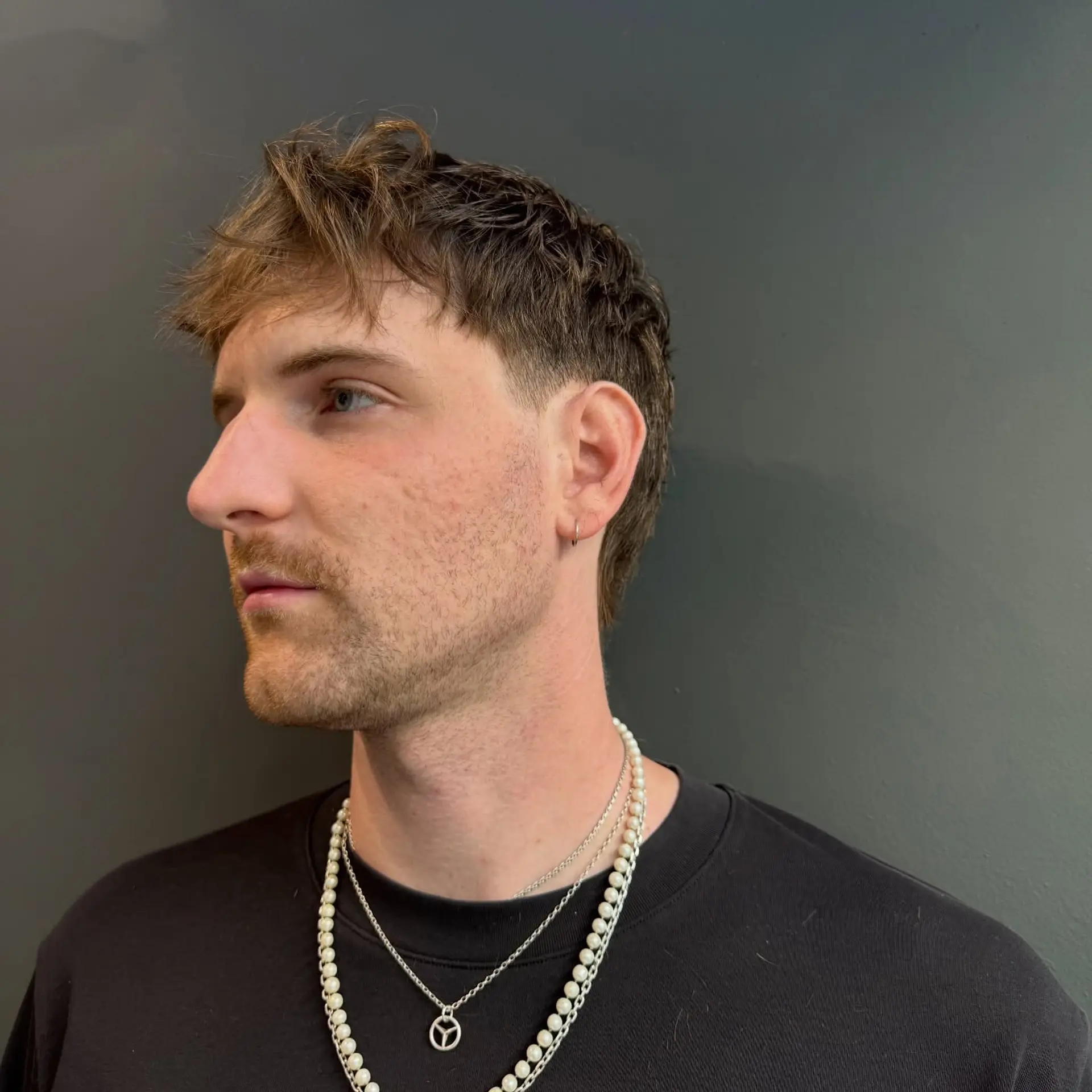 A textured modern mullet with a piecey fringe, tapered sides around the ear, and layered length at the nape. 1