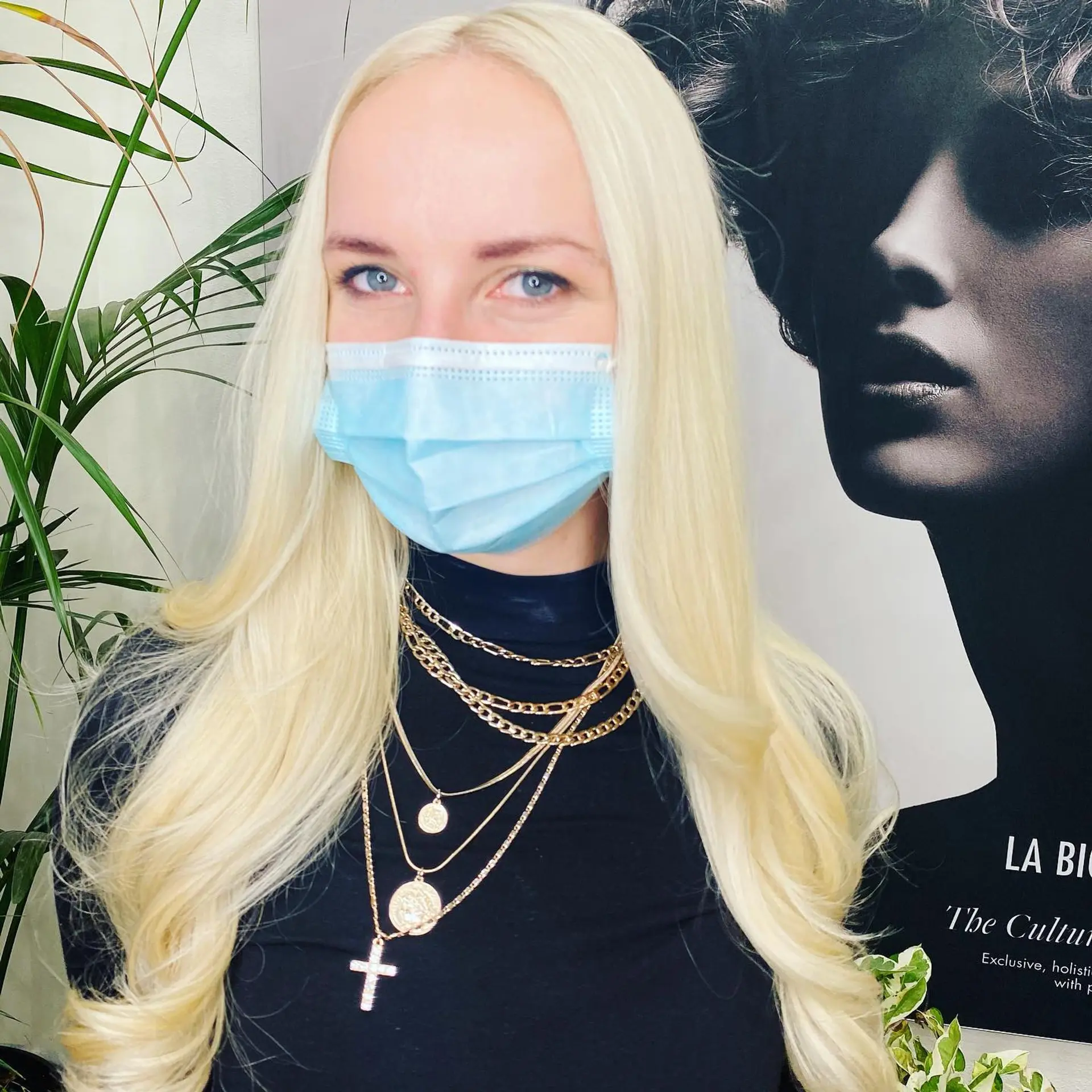 Luminous, all-over platinum bleach blonde hair styled smooth with softly curled ends framing the chest. 1