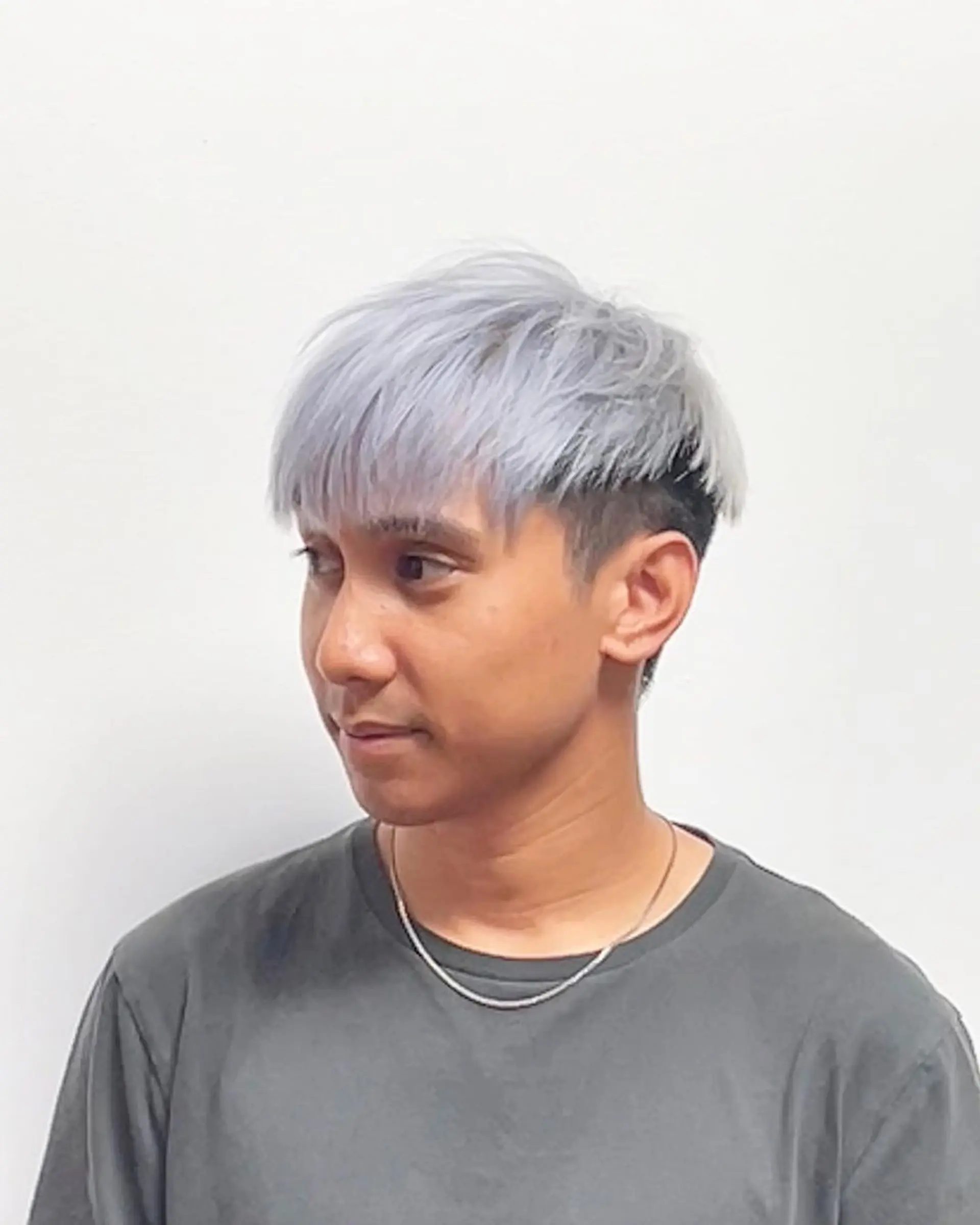 A modern and stylish short haircut characterized by straight silver and platinum colors, with a frosted fringe, dark undercut sides, and neatly layered top sections swept slightly to the side. 1