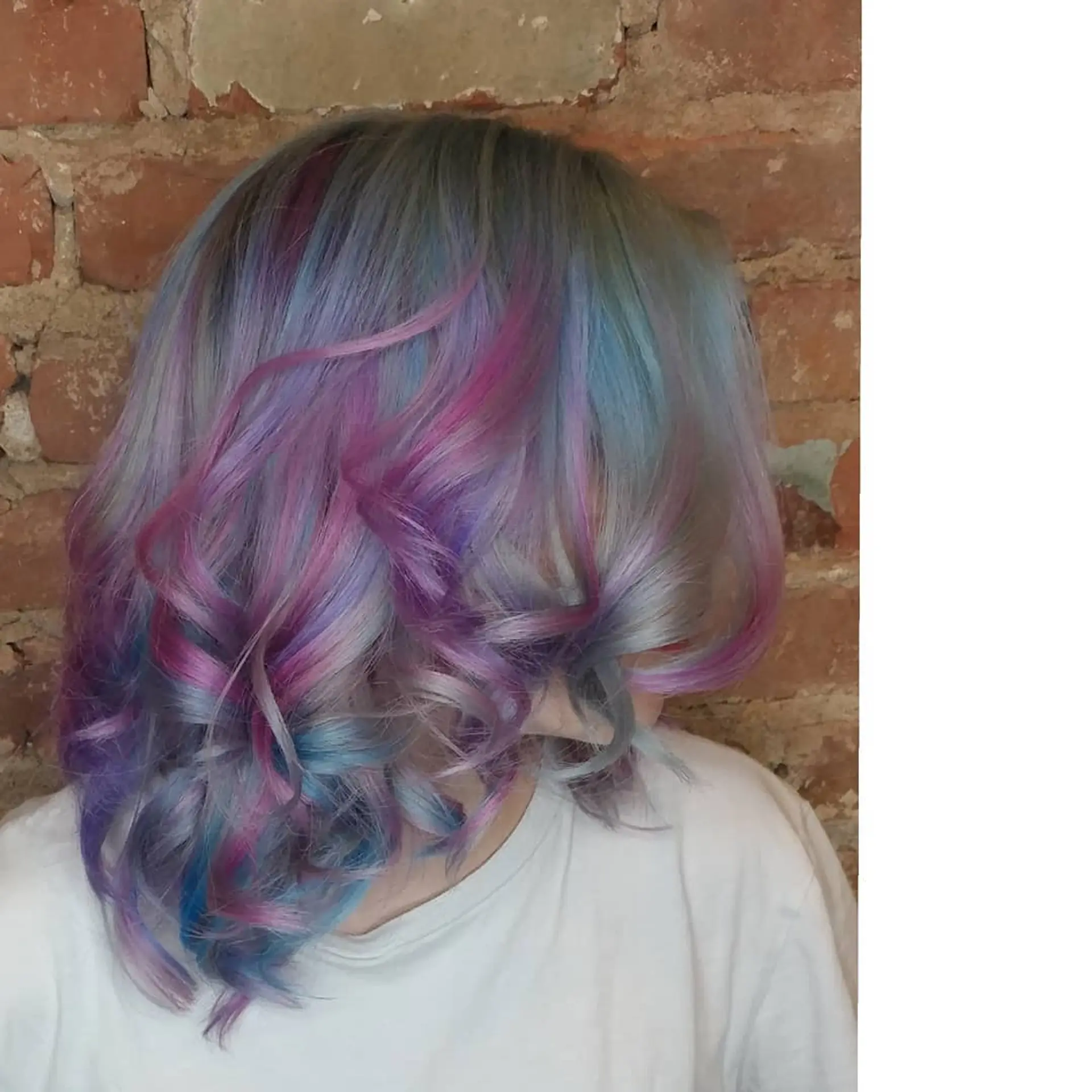 Medium-length hair featuring soft curls and multi-colored pastel shades of pink, lavender, and blue over a smoky silver base. 1