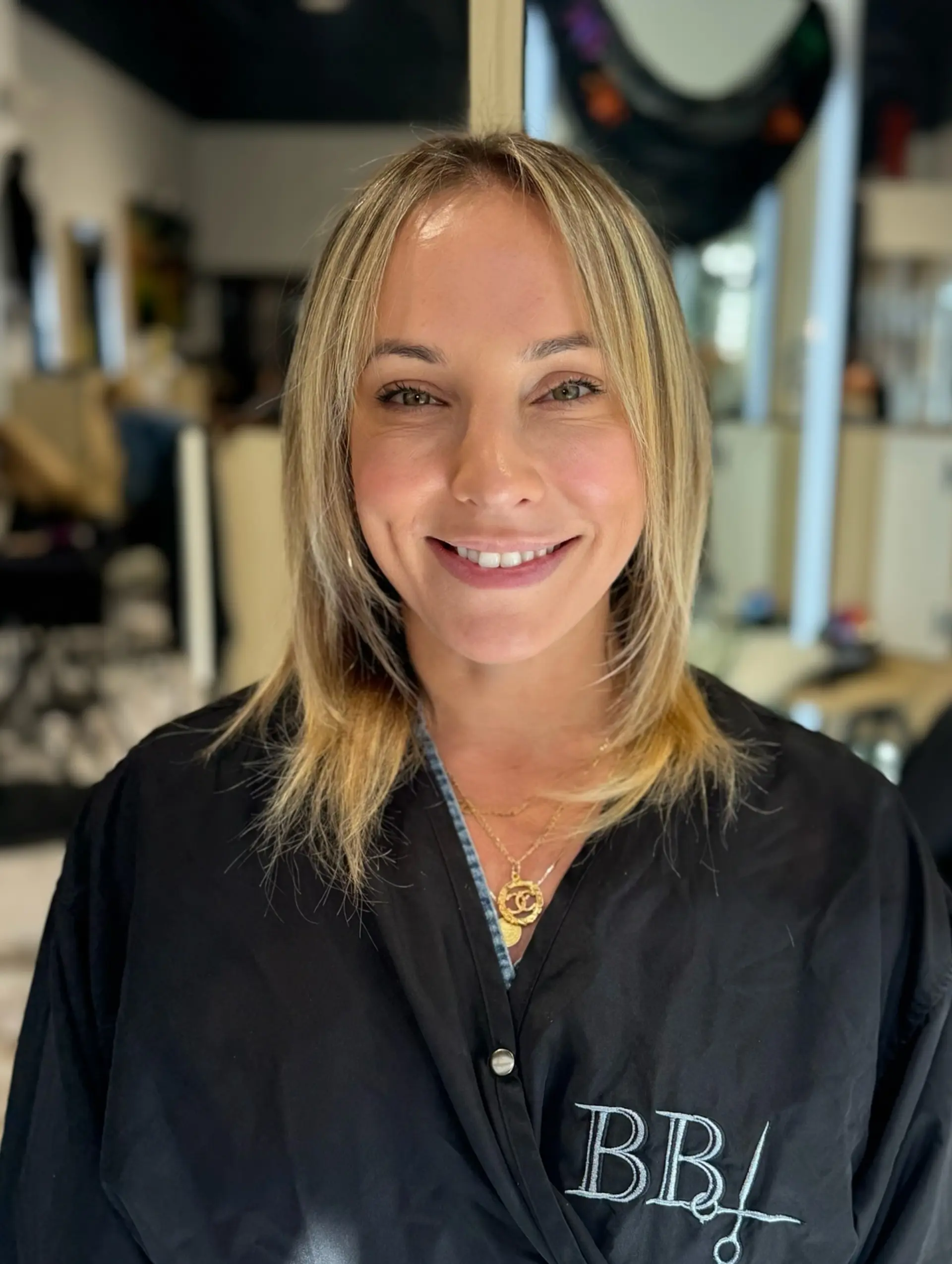 A medium-length layered cut styled smooth with soft face-framing layers and dimensional golden blonde tones. 1