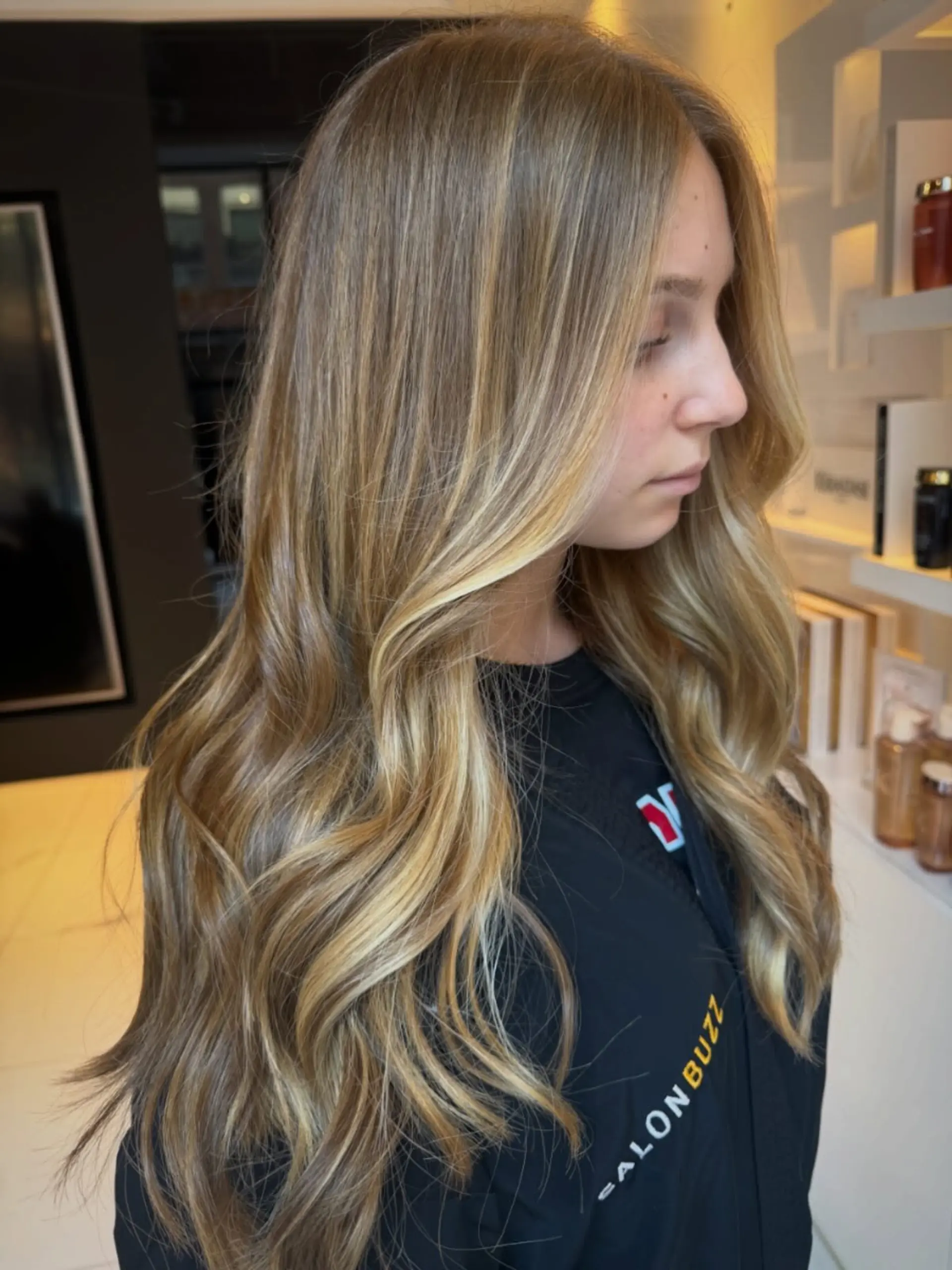 Long, dimensional golden blonde balayage styled with soft, cascading waves. 1