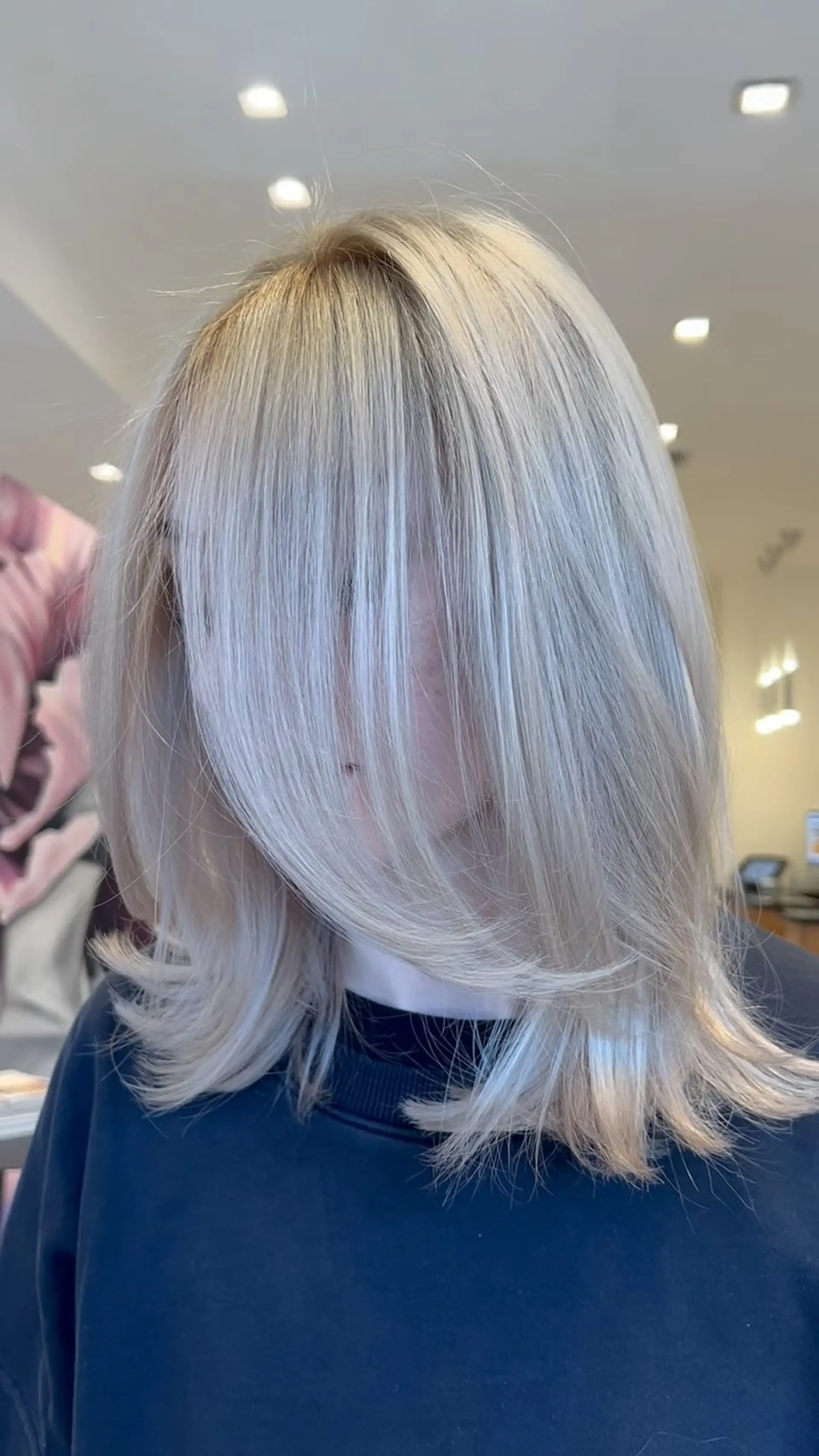 A sleek shoulder-length platinum blonde hairstyle featuring face-framing curtain fringe and delicately flipped ends. 1