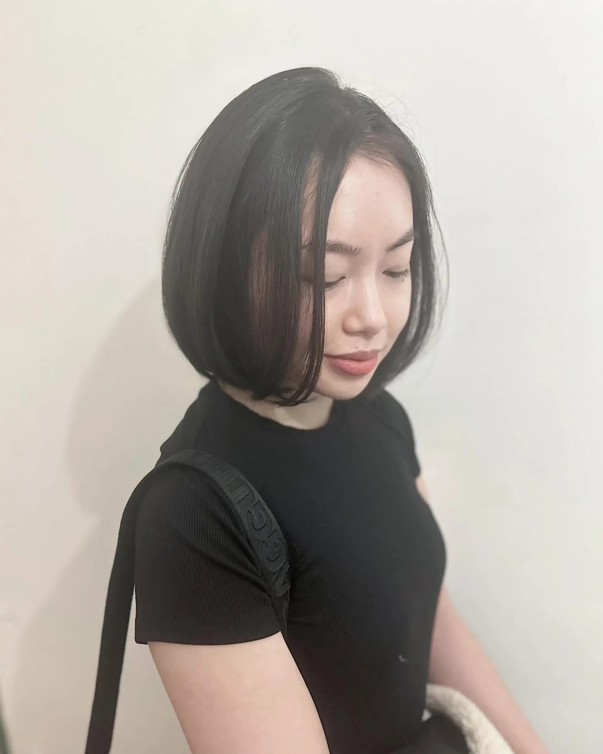 A sophisticated chin-length bob cut, characterized by its sleek, straight texture and ends that gently curl inward. This style provides a rounded, voluminous shape, framing the face beautifully with a natural part. 1