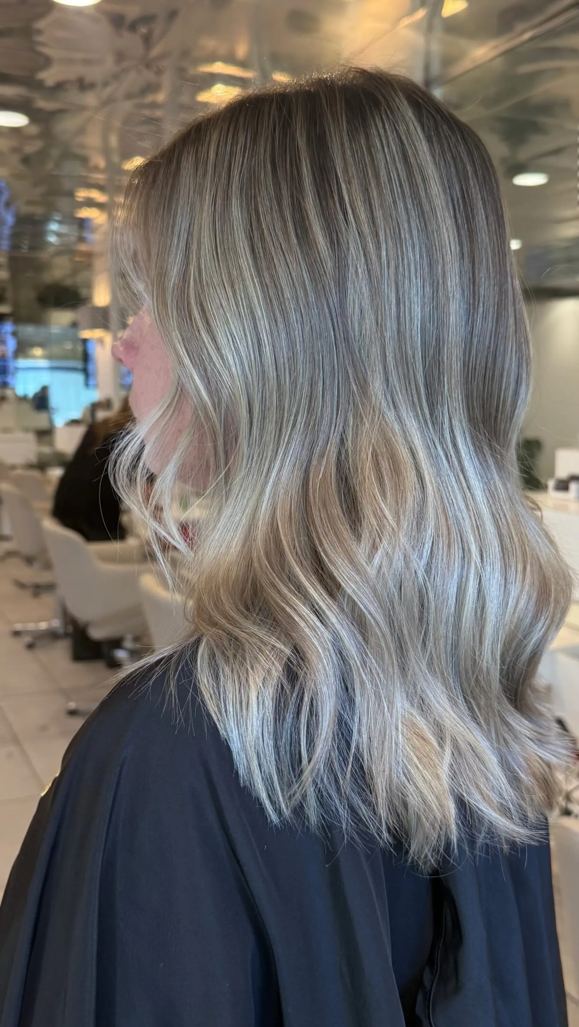 Medium-length beige blonde hair styled with loose, polished waves highlighting soft multi-dimensional tones. 1