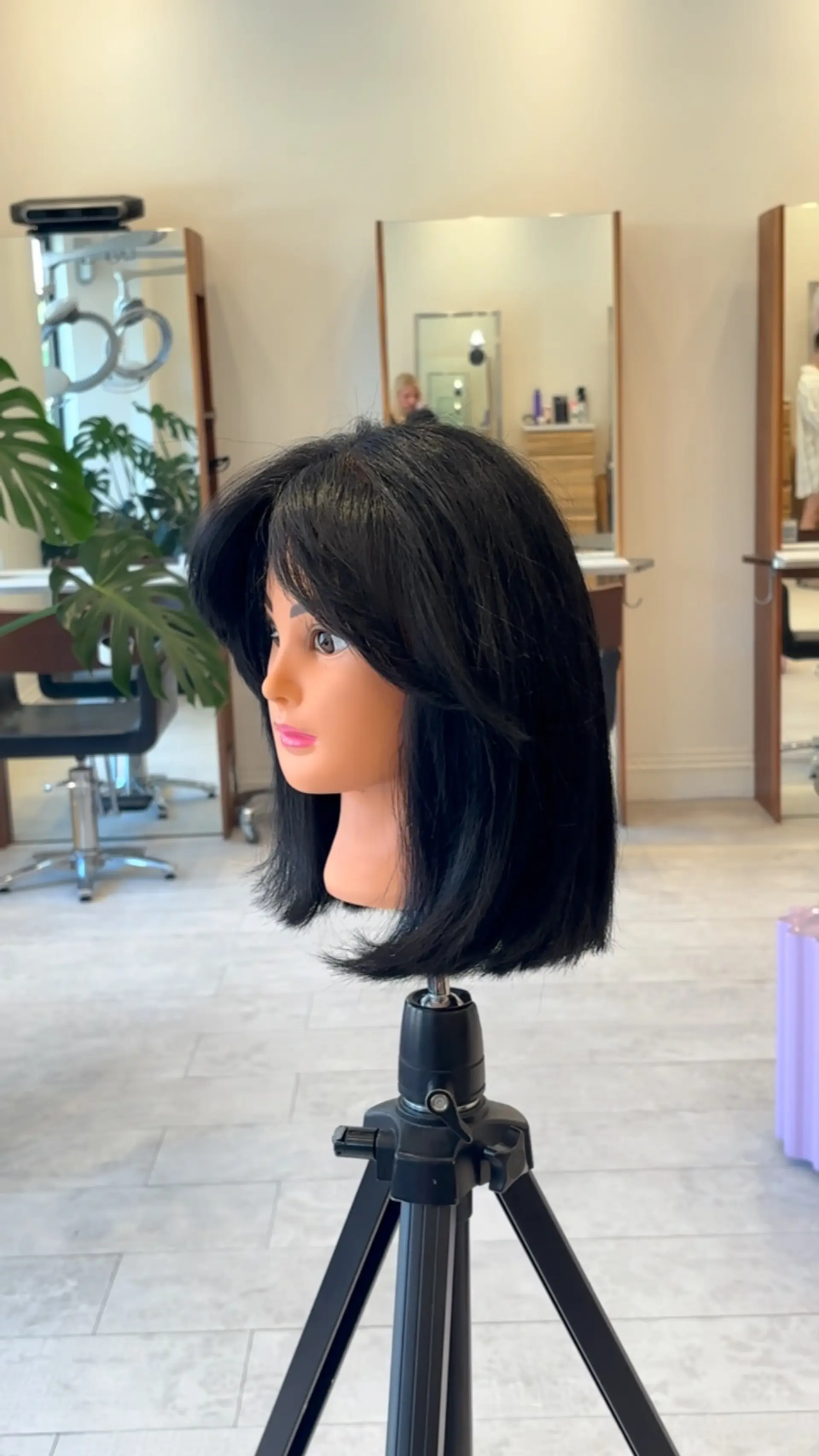 A sleek black layered bob haircut featuring soft curtain bangs and textured, face-framing layers. 1