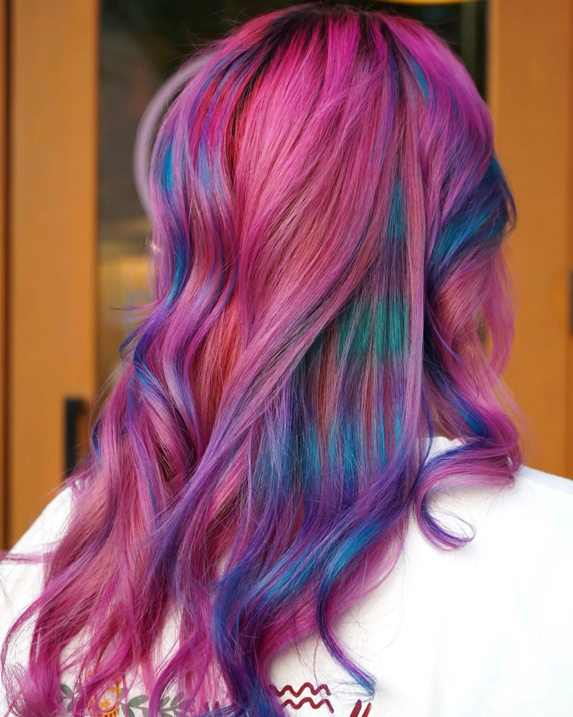 Vibrant long hair with a multi-tonal blend of bright pink, purple, teal, and blue styled in loose waves. 1