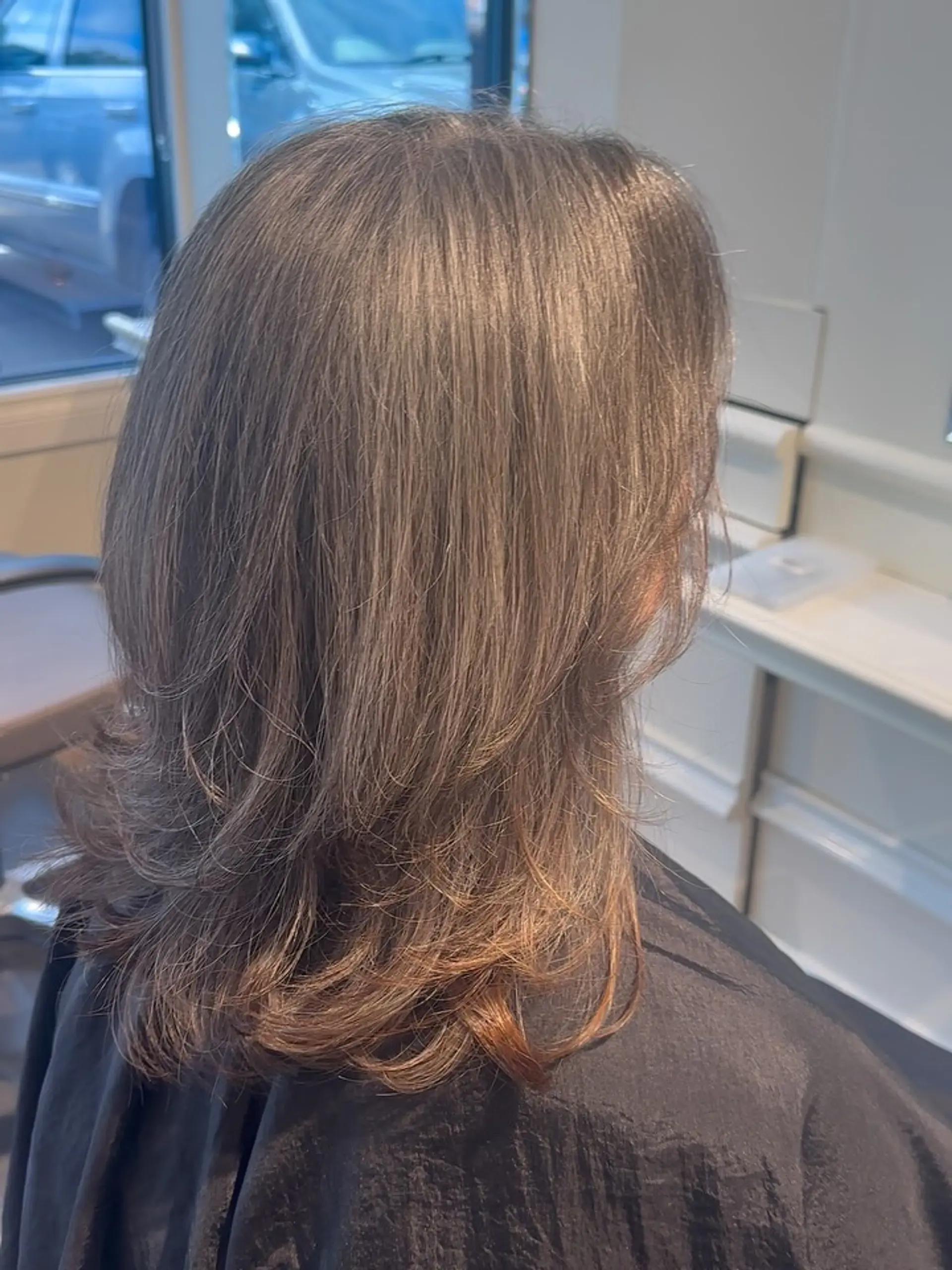 Medium-length layered haircut styled with soft, flipped-out ends for subtle volume and motion. 1