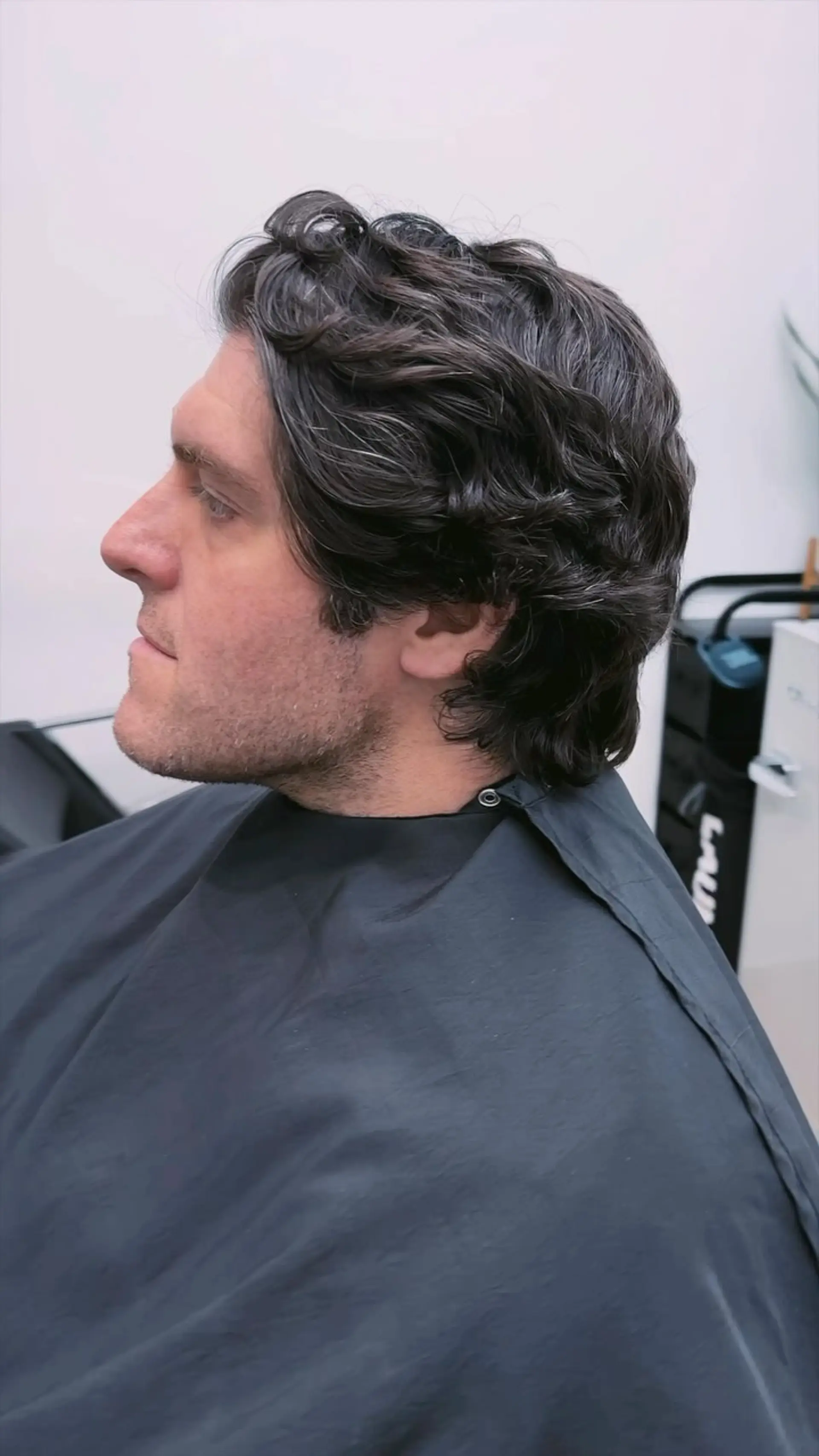 A classic medium-length scissor cut featuring natural wavy texture swept back, neatly shaped around the ears and neckline. 1