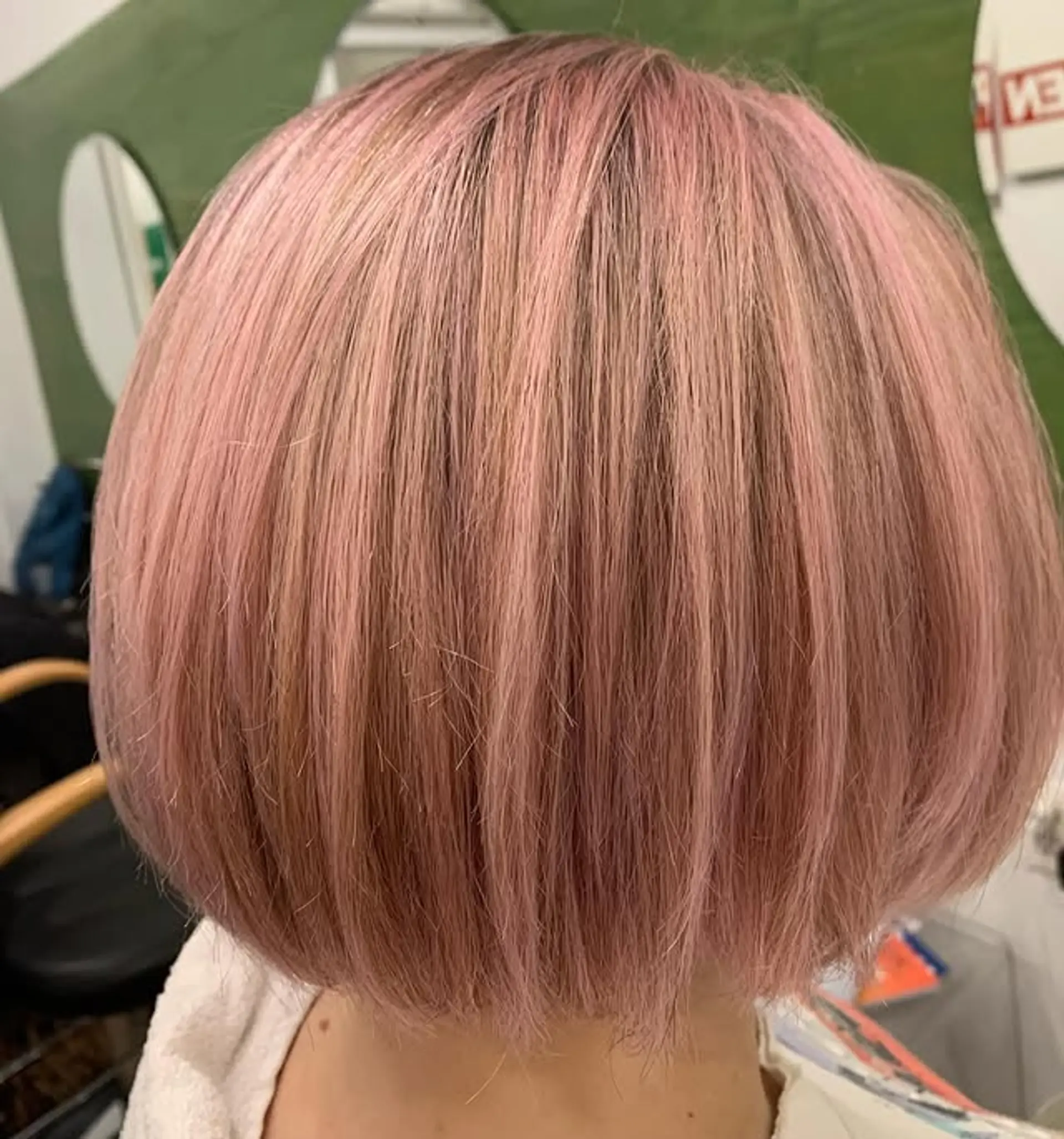 A modern blunt bob cut with a clean, chin-length line and a dusty rose blonde color. 1