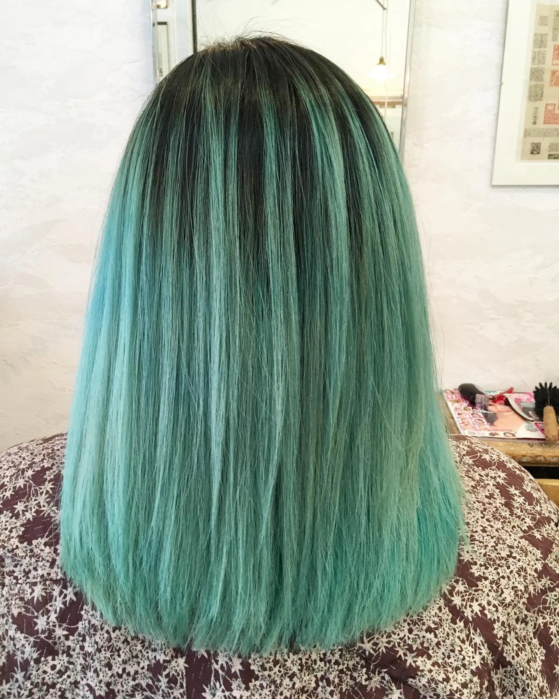 A striking medium-length straight cut, predominantly dyed in a vibrant aqua green transitioning from darker roots. The straight texture enhances the lively color, providing a sleek and smooth finish. 1
