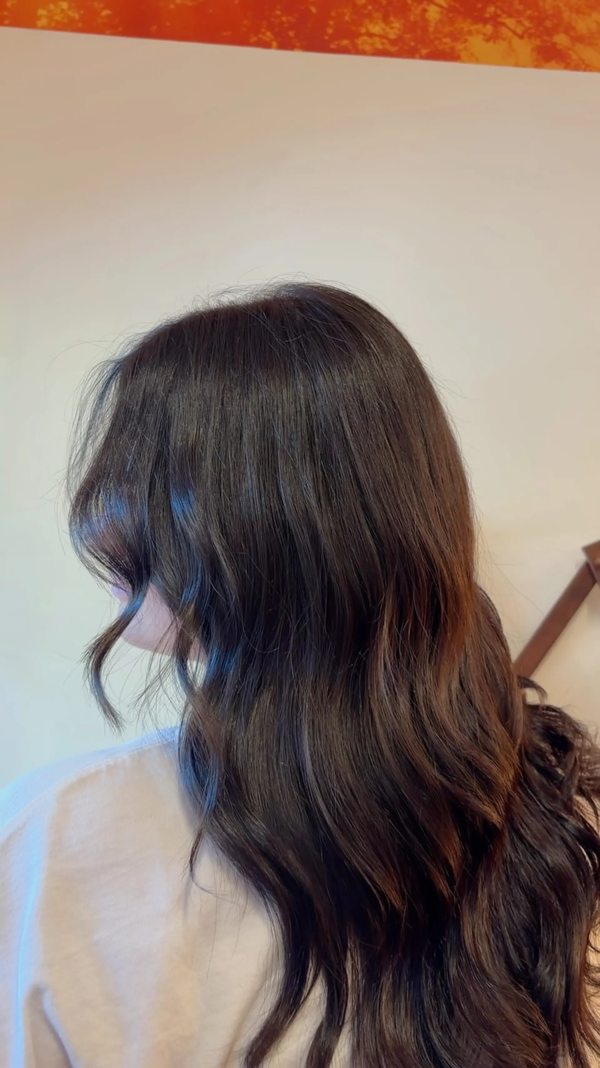 Rich, glossy dark brunette hair cut with soft layers and styled into loose, shiny waves with curtain bangs. 1