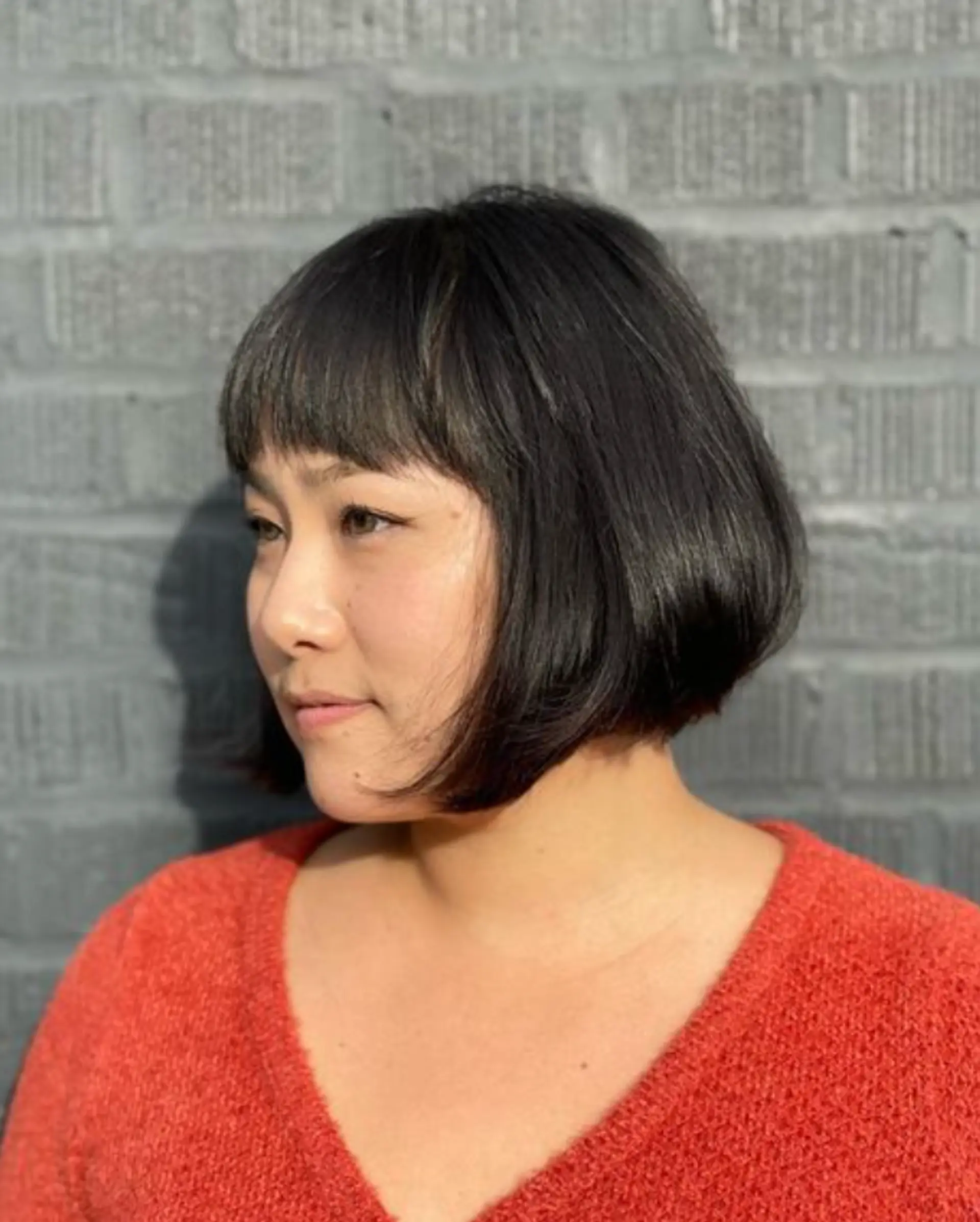 A sleek black bob with a side fringe and textured ends, showcasing a natural shine. 1