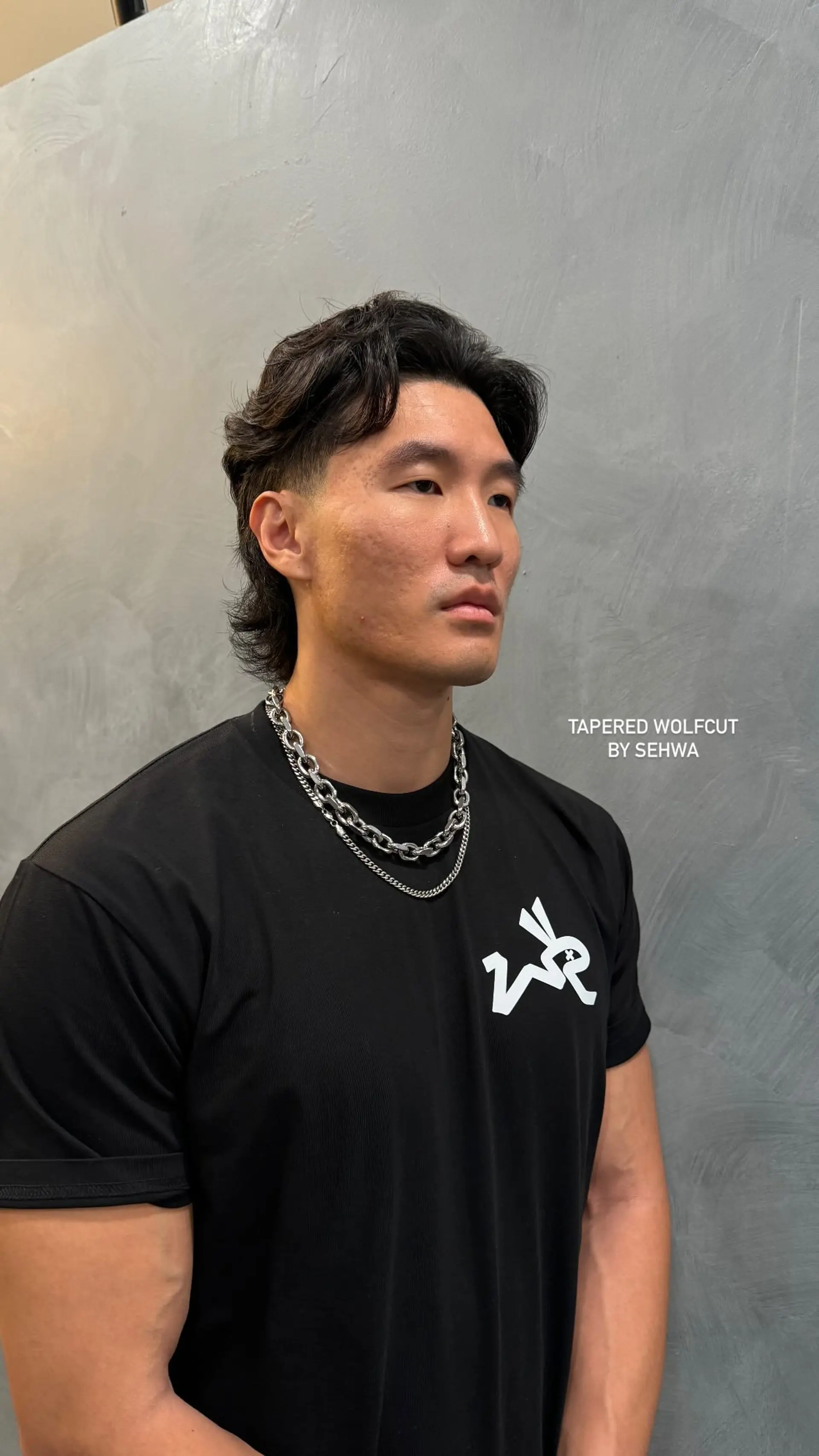 A trendy tapered wolfcut with short sides and medium length at the back, styled with a wavy texture. 1