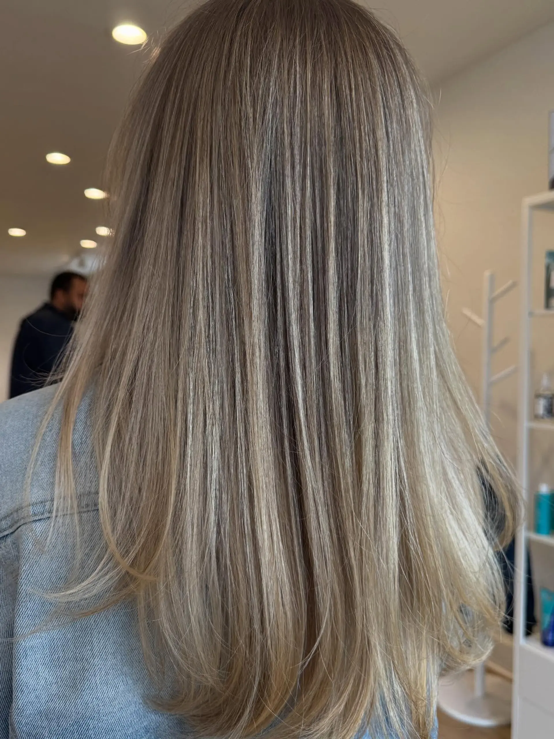 Long, smooth straight hair featuring finely blended ash blonde highlights over a light brown base with softly curved ends. 1