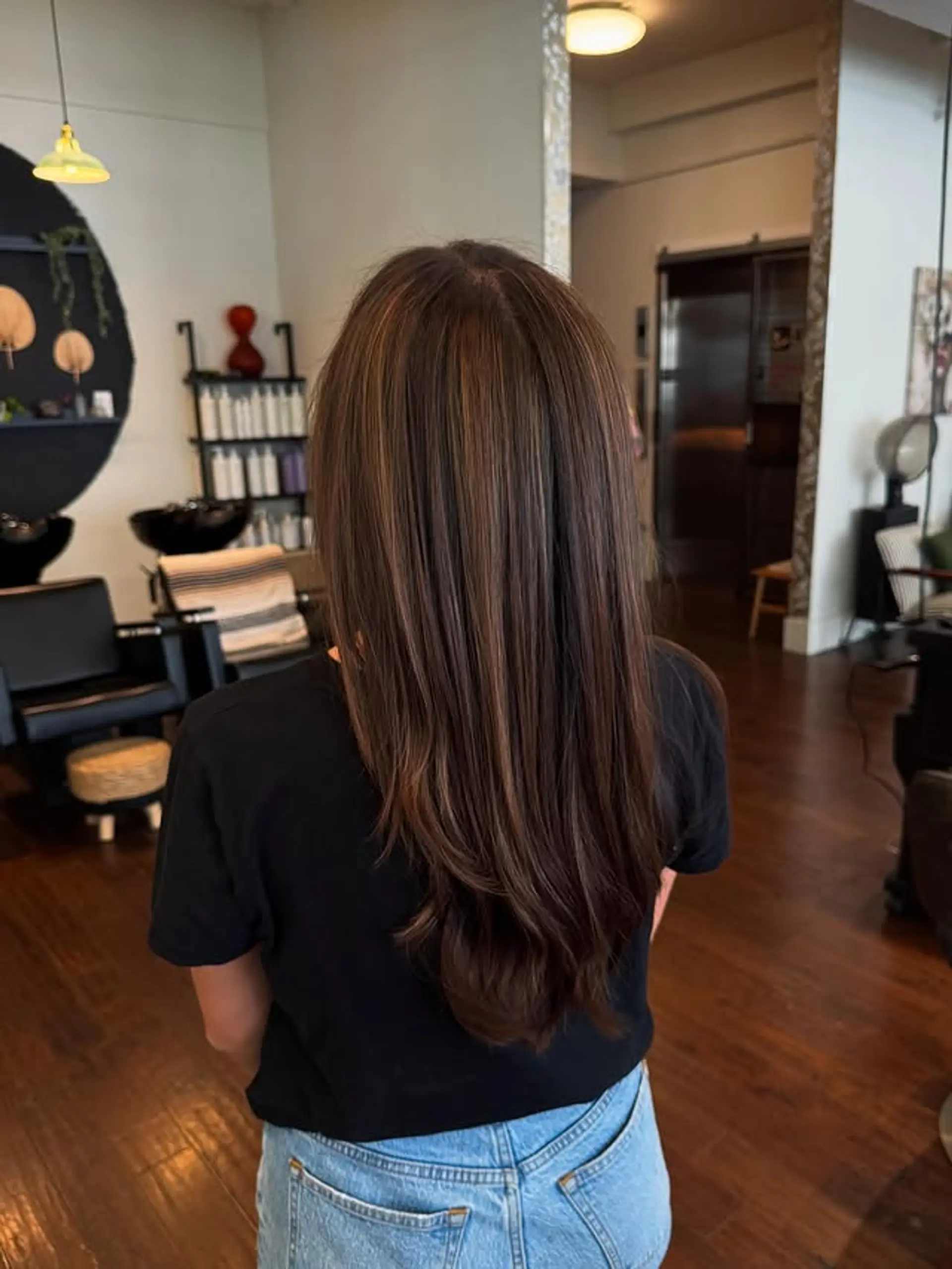 A long, straight layered hairstyle with subtle blonde highlights. 1