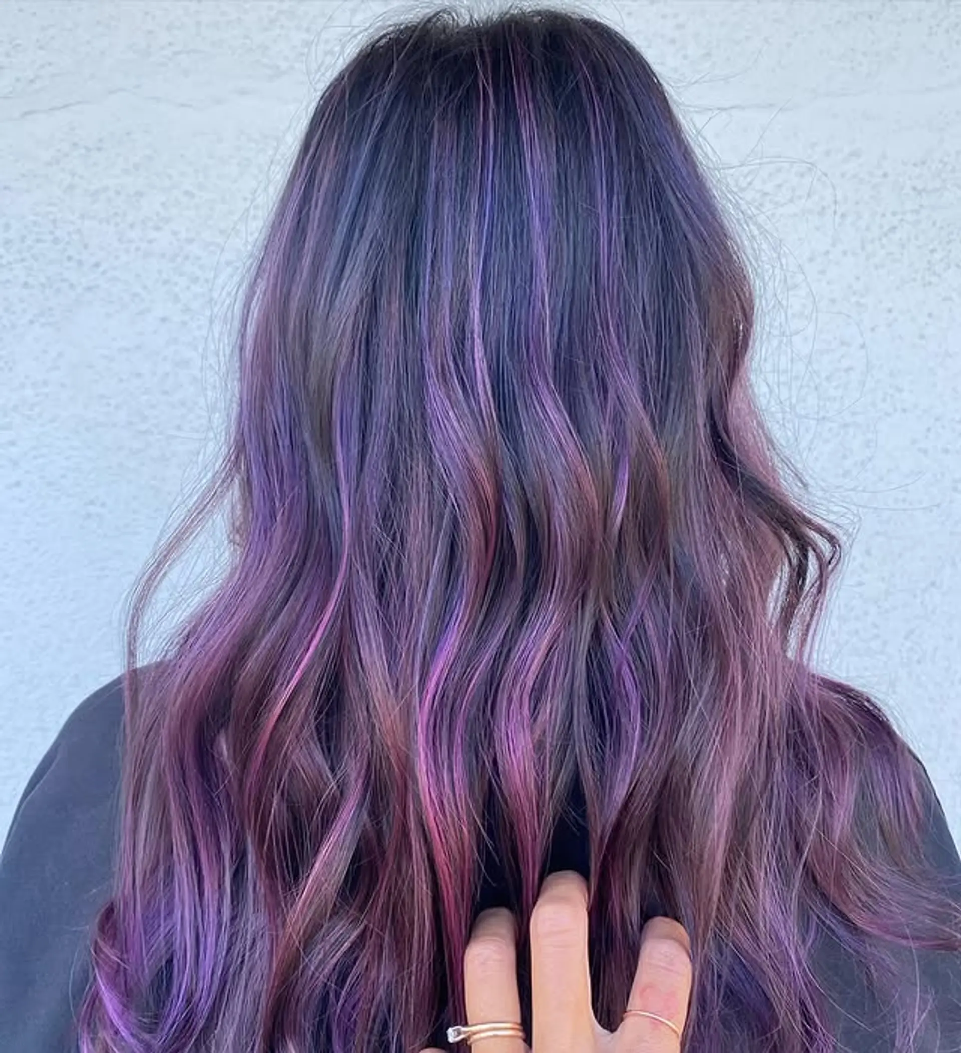 A wavy, long hairstyle featuring a multi-toned purple and pink balayage. 1