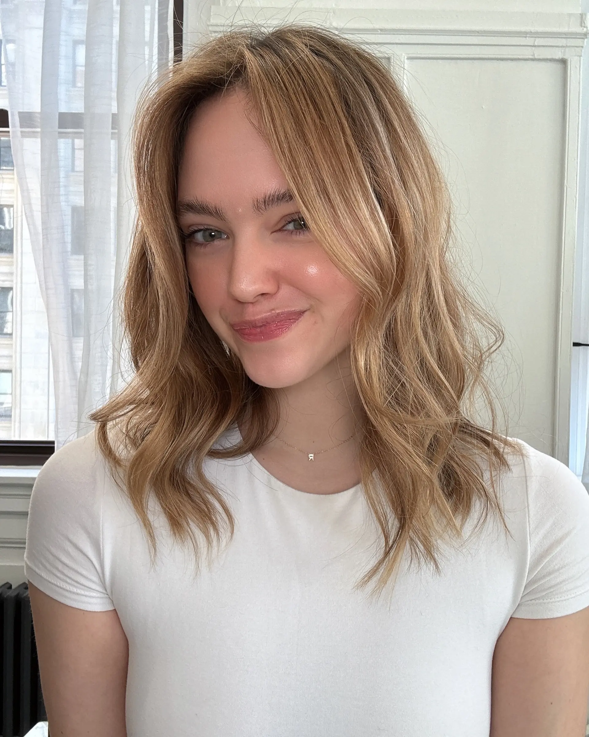 Collarbone-length layered cut styled in effortless, soft waves with warm bronde balayage highlights. 1