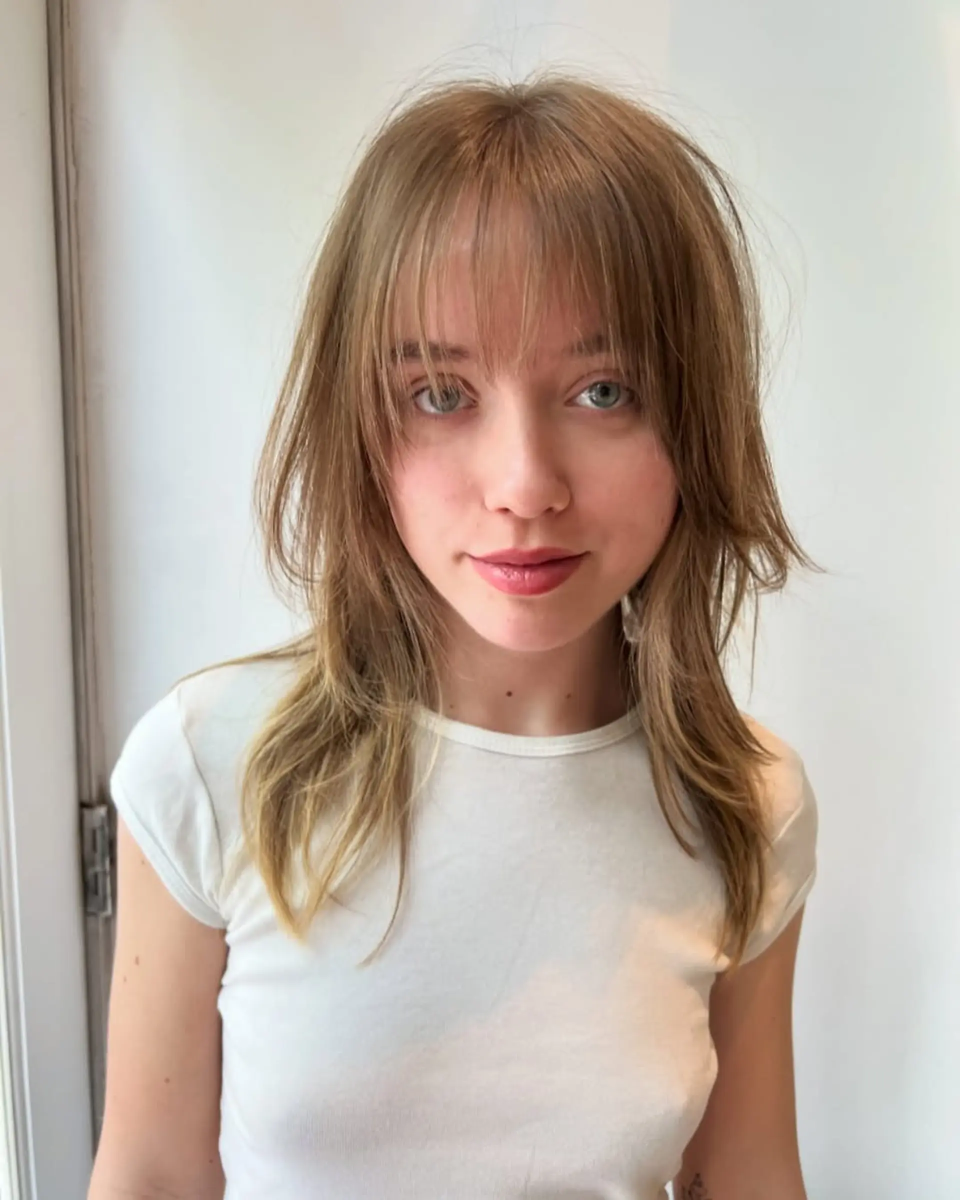 A medium-length shag haircut with face-framing layers and baby bangs. 1