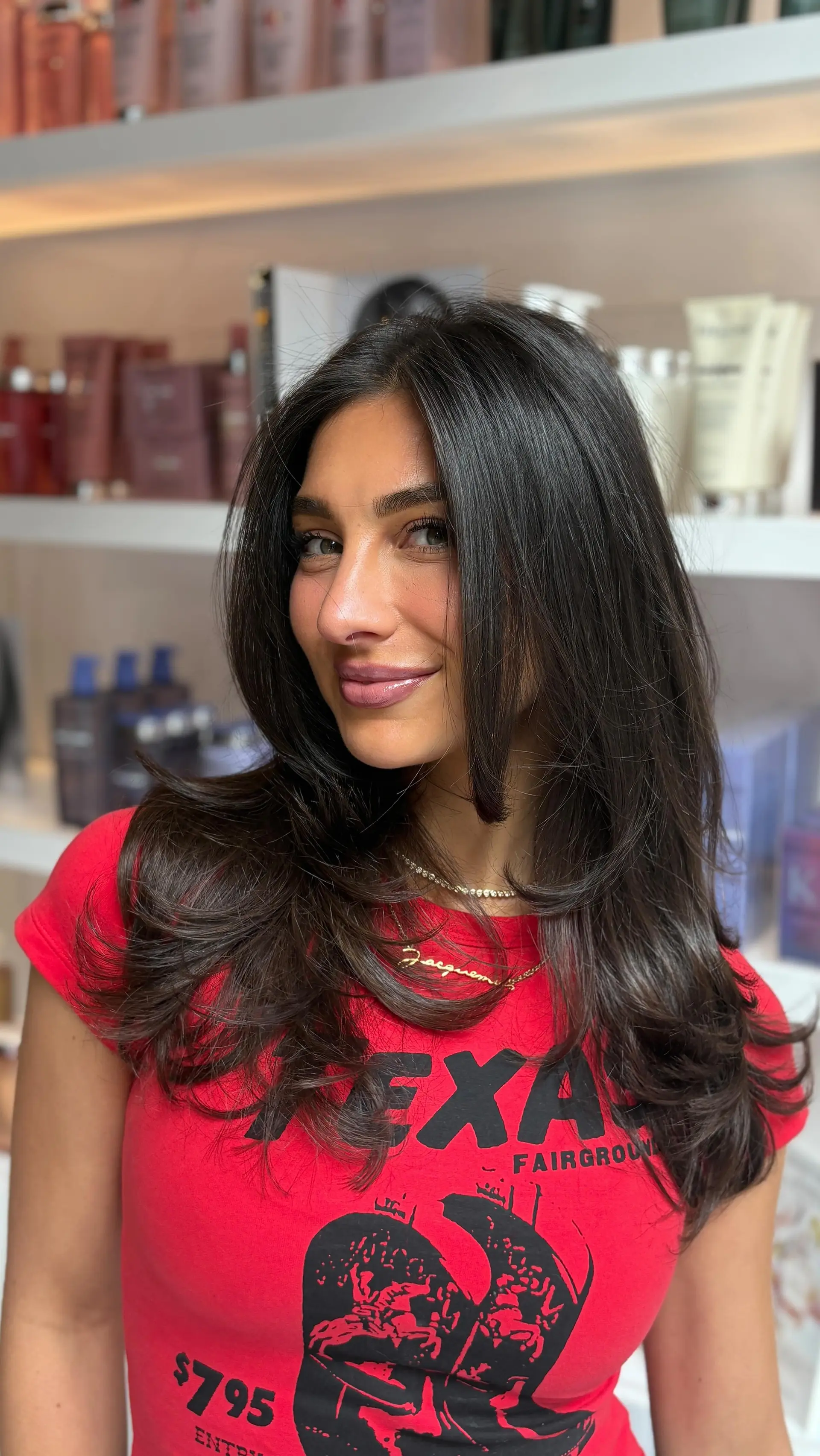 Long dark brown hair cut with soft face-framing layers and styled into a voluminous, bouncy blowout with curled ends. 1