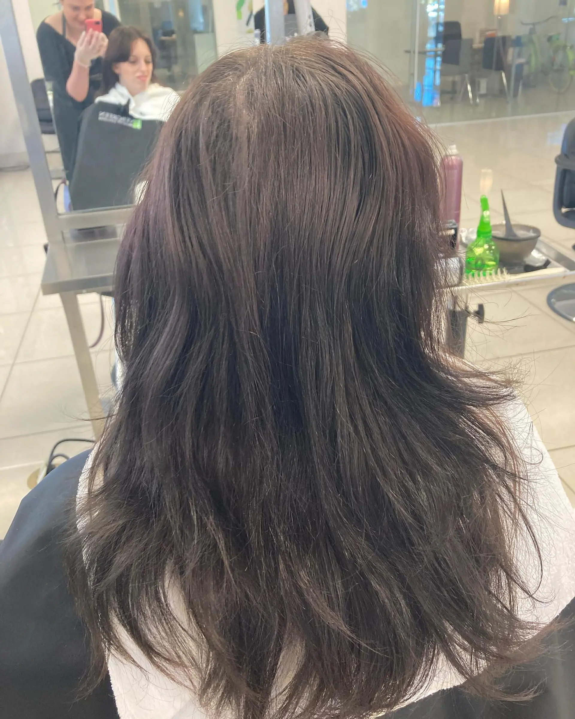 A textured long shag haircut styled with blended layers and cool-toned reddish undertones. 1