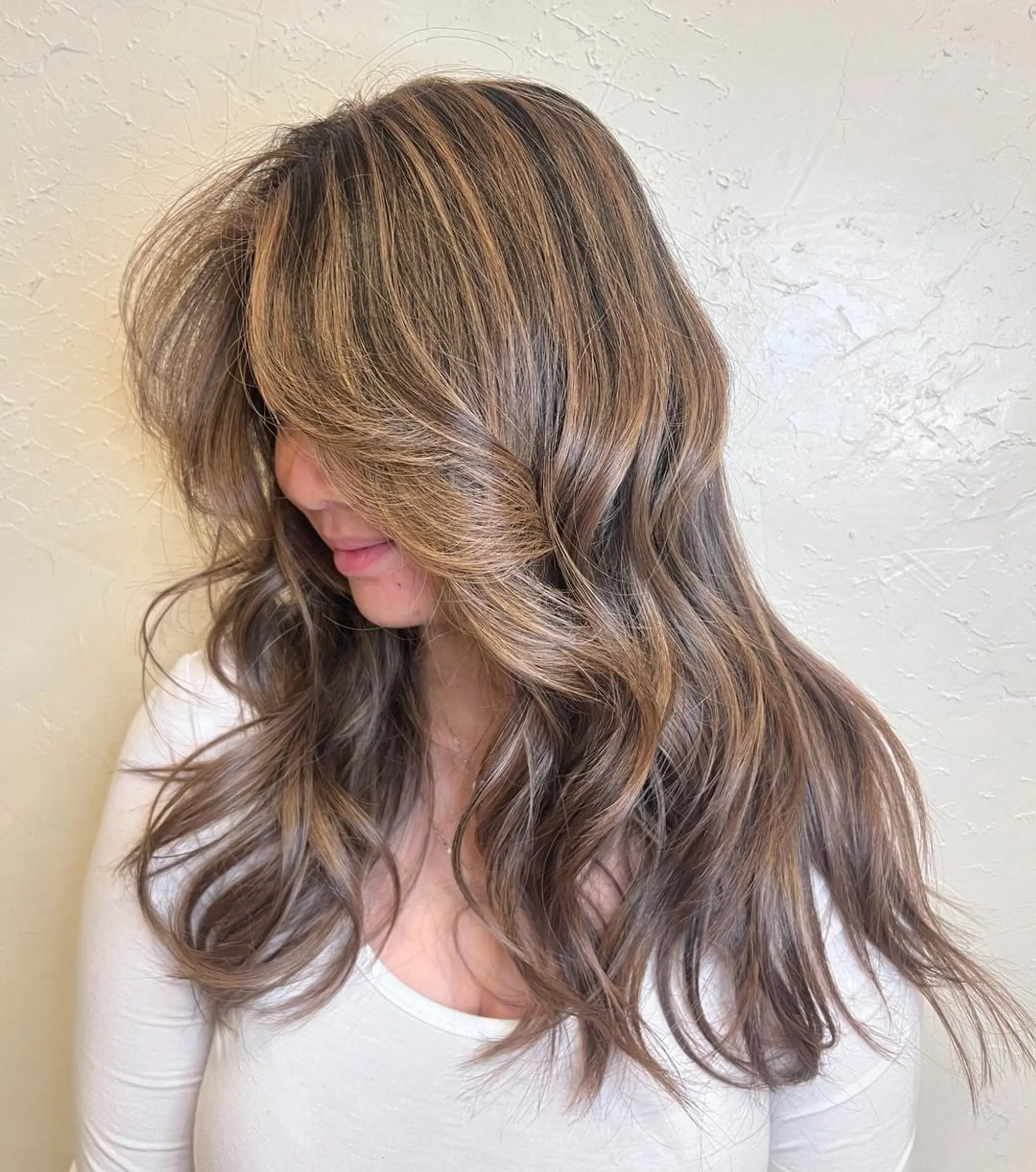 Long, wavy hair with a blend of bronze, golden blonde, and dark brown hues, featuring face-framing highlights, natural shine, and a voluminous, layered appearance. 1
