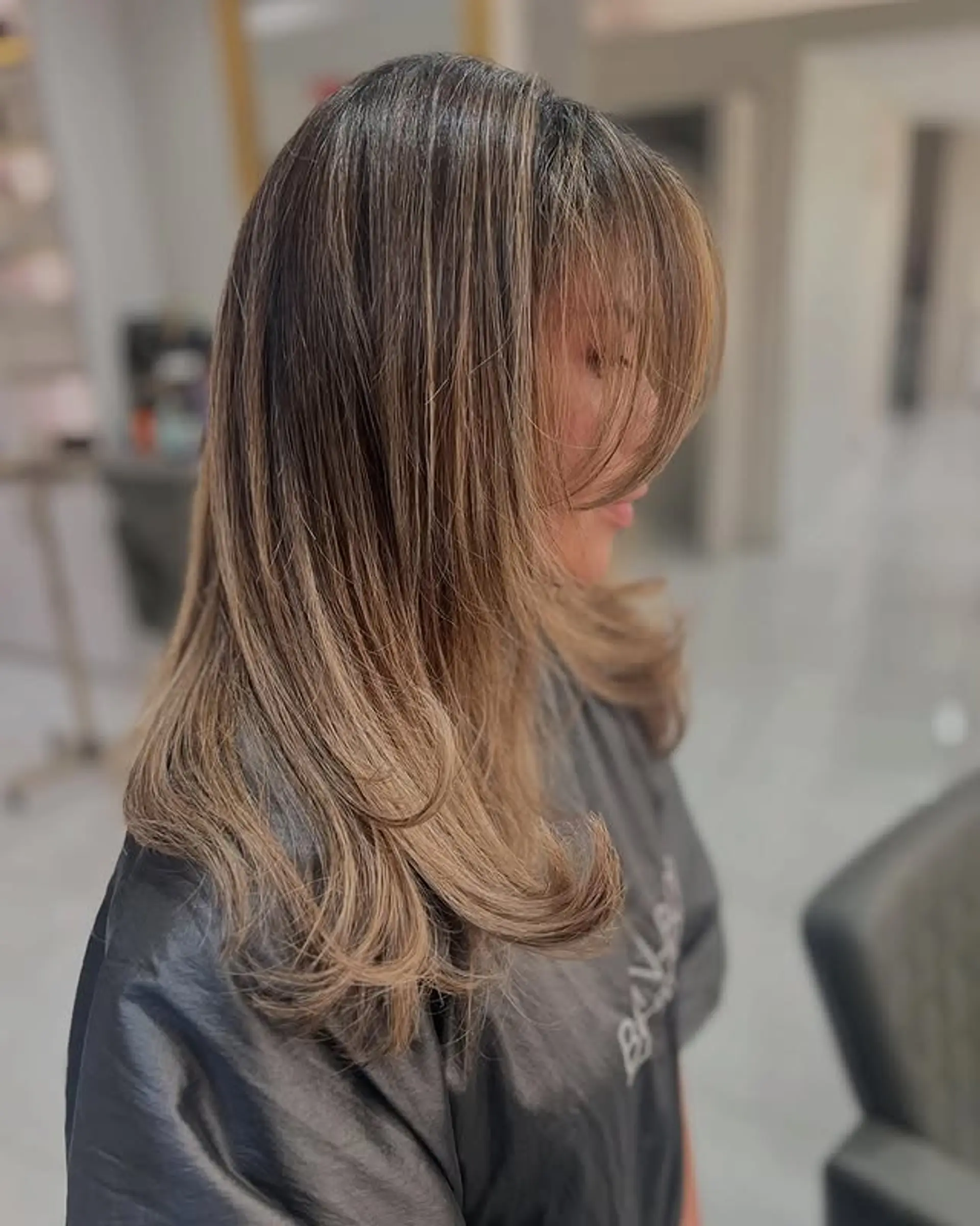 Medium length with a caramel swirl balayage, face-framing layers, and curtain bangs. 1