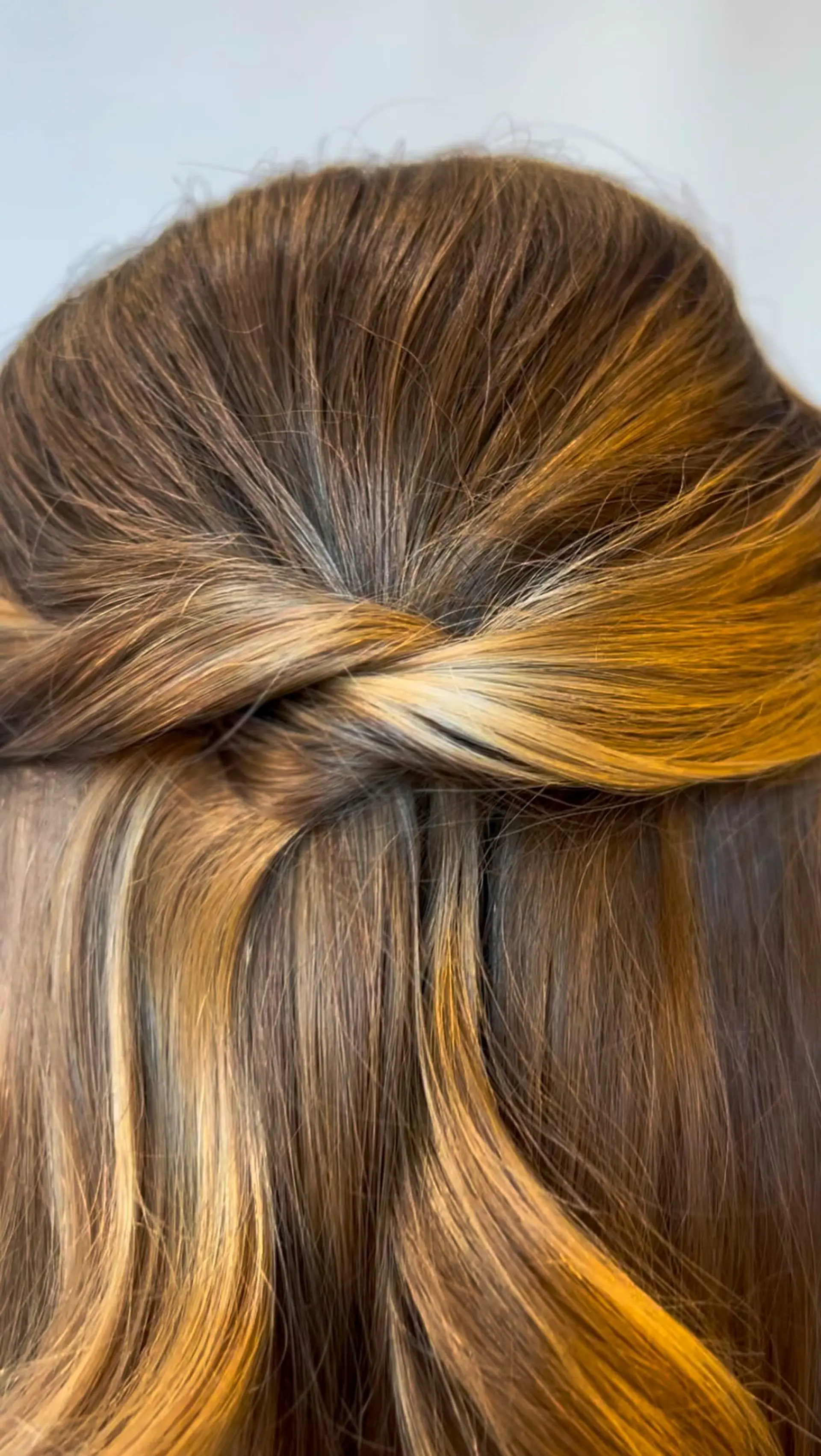 An elegant half-up style featuring two twisted strands overlapping neatly at the back of the head, cascading into soft dimensional waves. 1