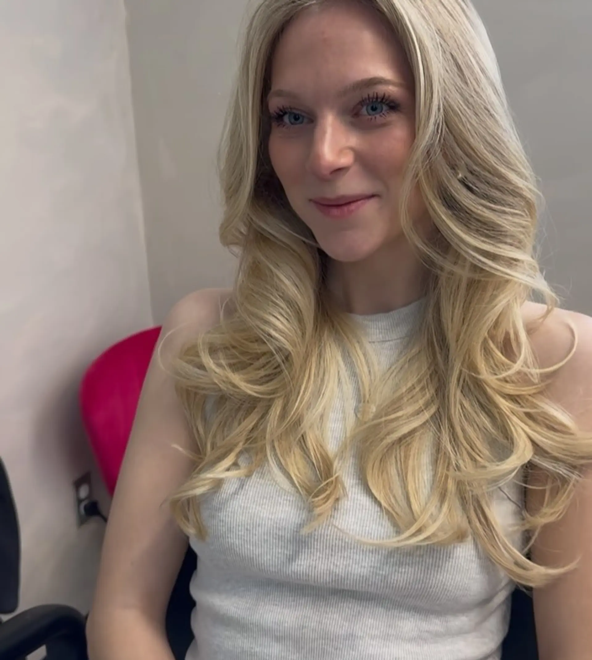 Long layered blonde hair styled into a bouncy, voluminous blowout with softly flipped ends and curtain-style face framing. 1