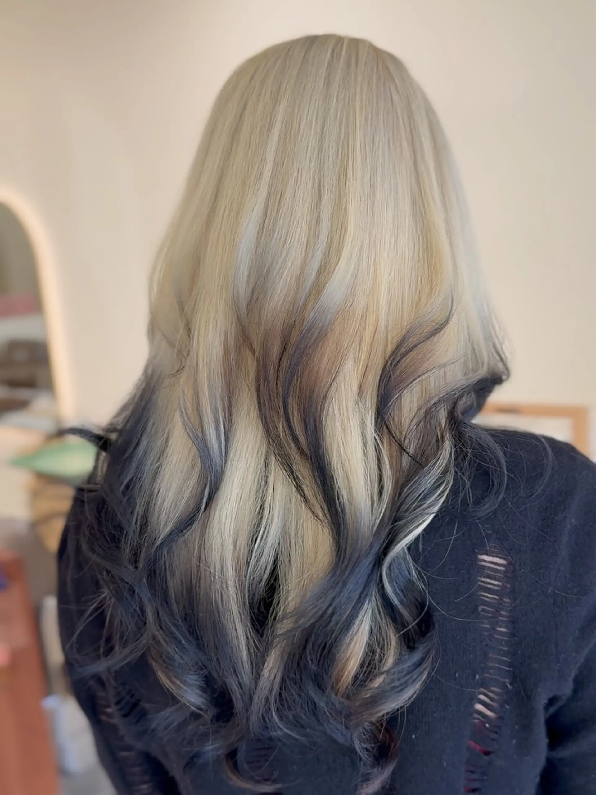 Long platinum blonde hair styled with soft waves and contrasting dark charcoal-blue dipped ends. 1