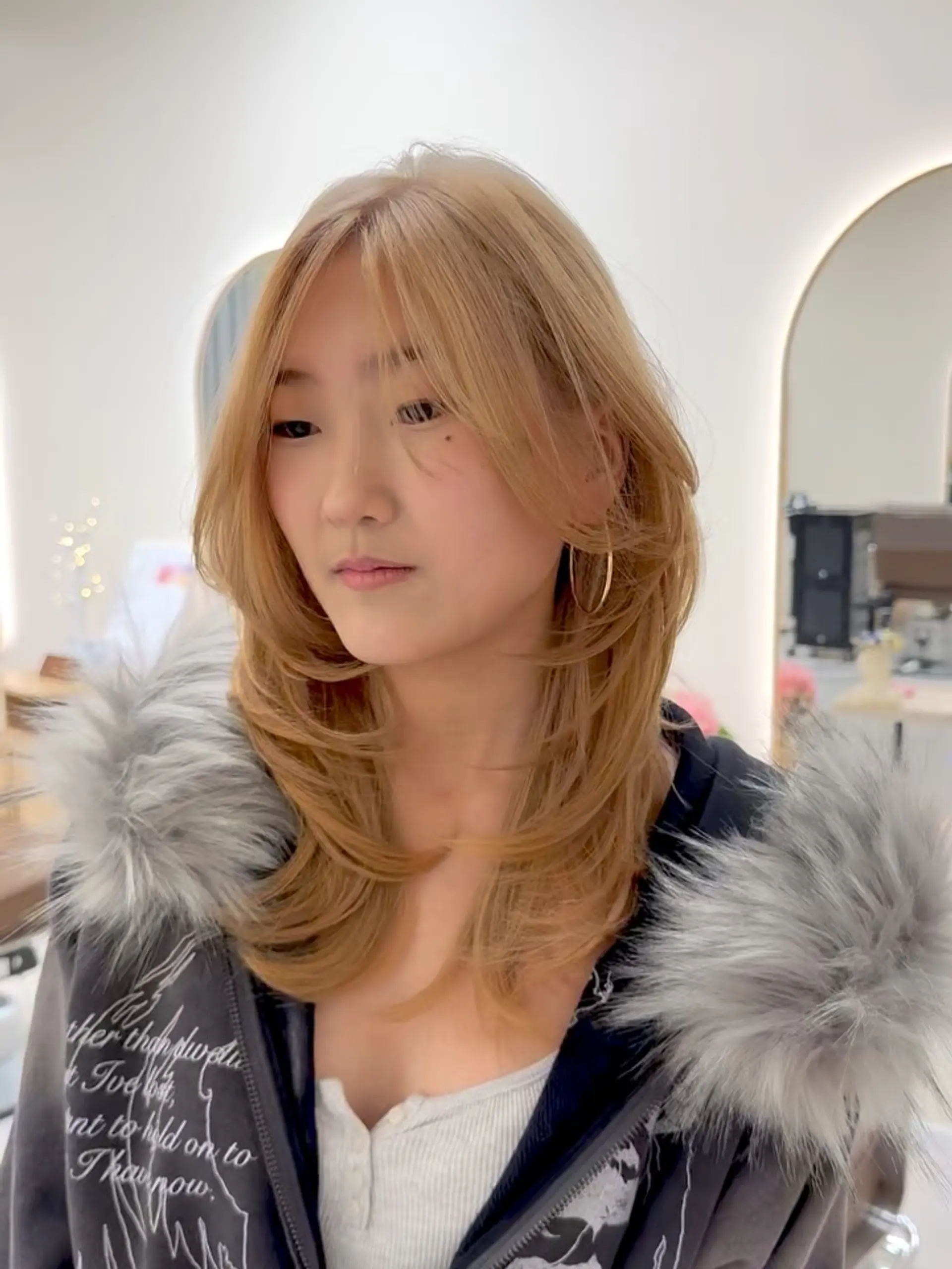 Medium-length warm blonde hair styled with inward-curling face-framing layers and parted curtain fringe. 1