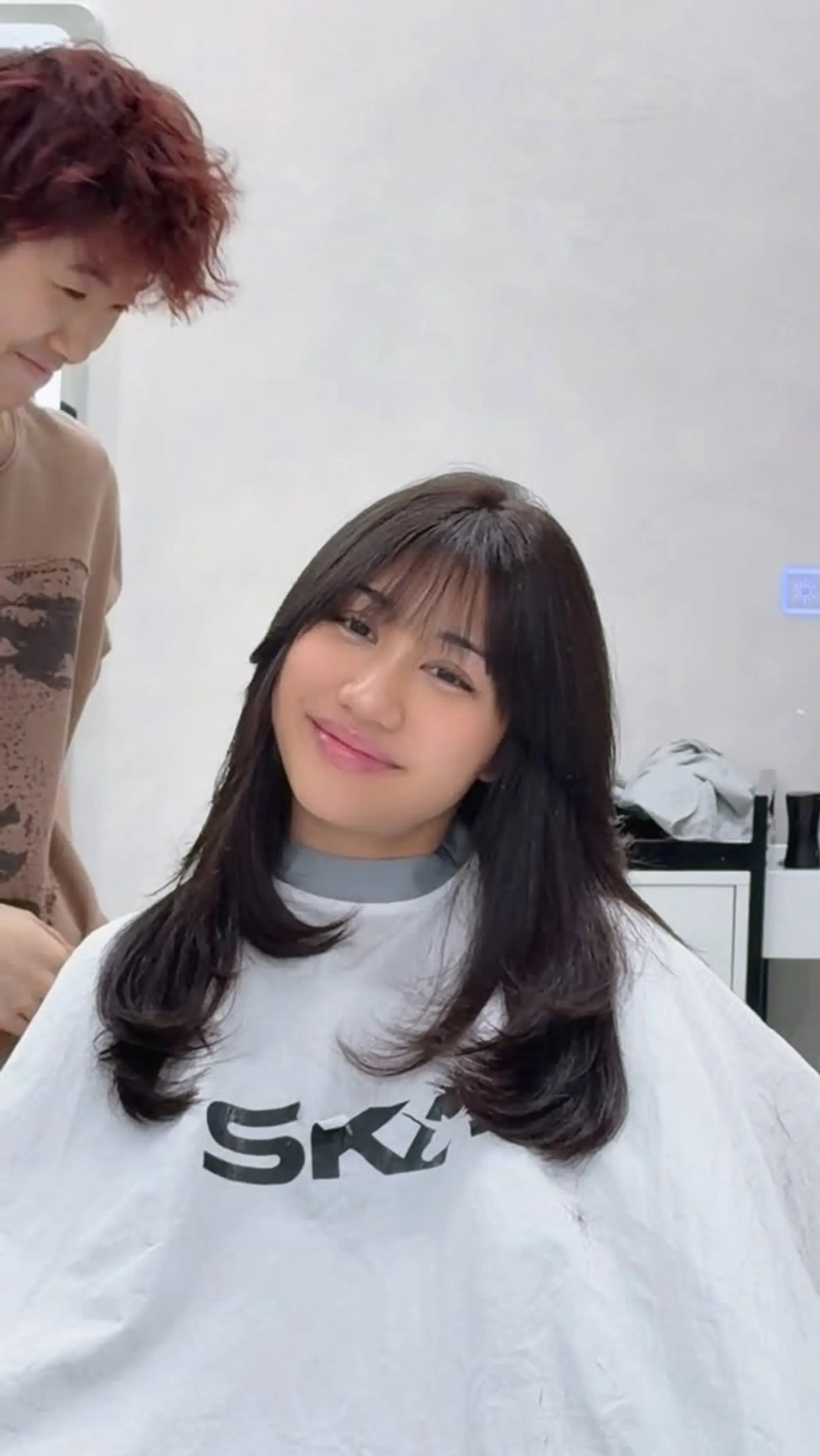 Medium-to-long layered brunette haircut featuring soft C-curl ends and light see-through fringe bangs. 1
