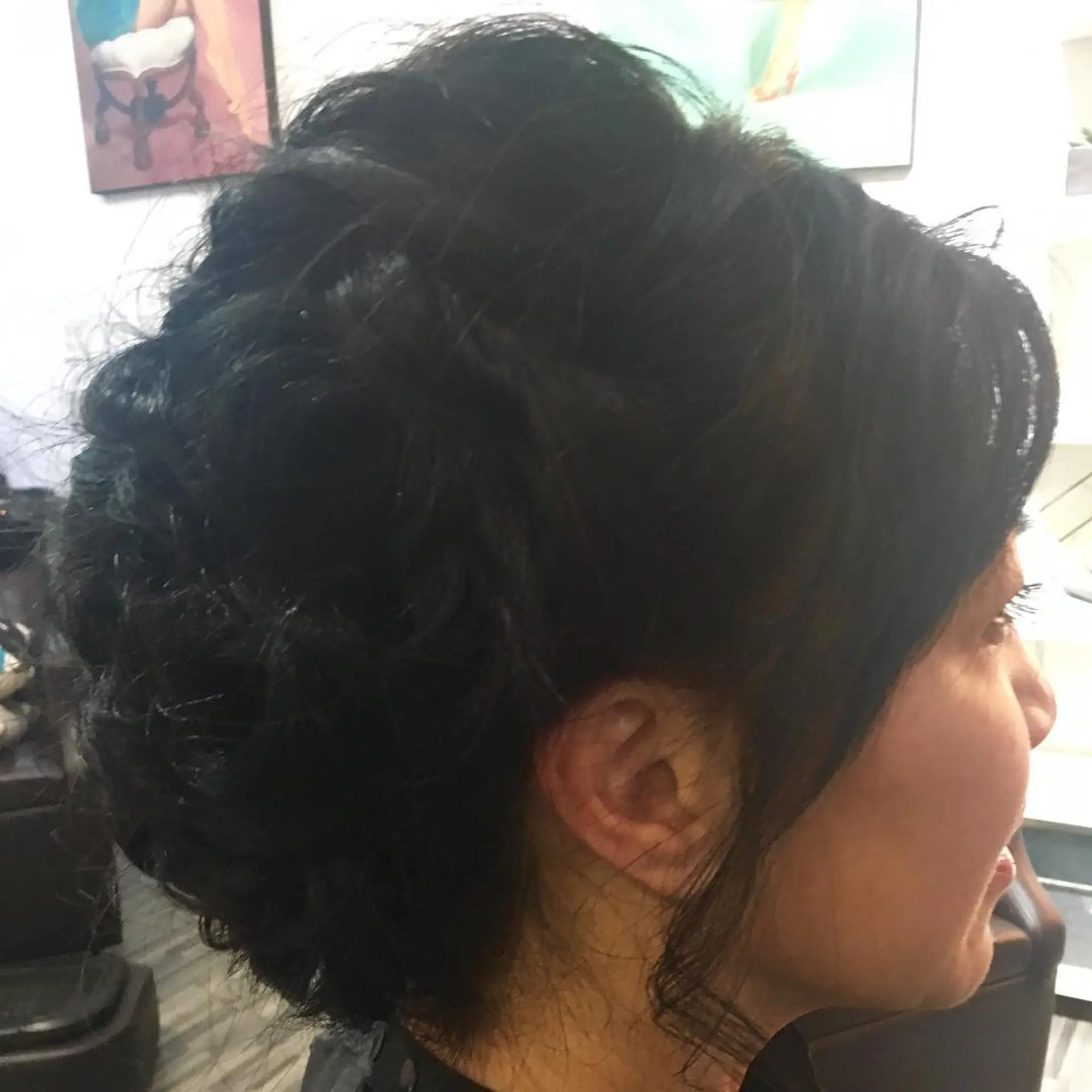 An elegant textured black updo with softly pinned curls and subtle face-framing tendrils. 1