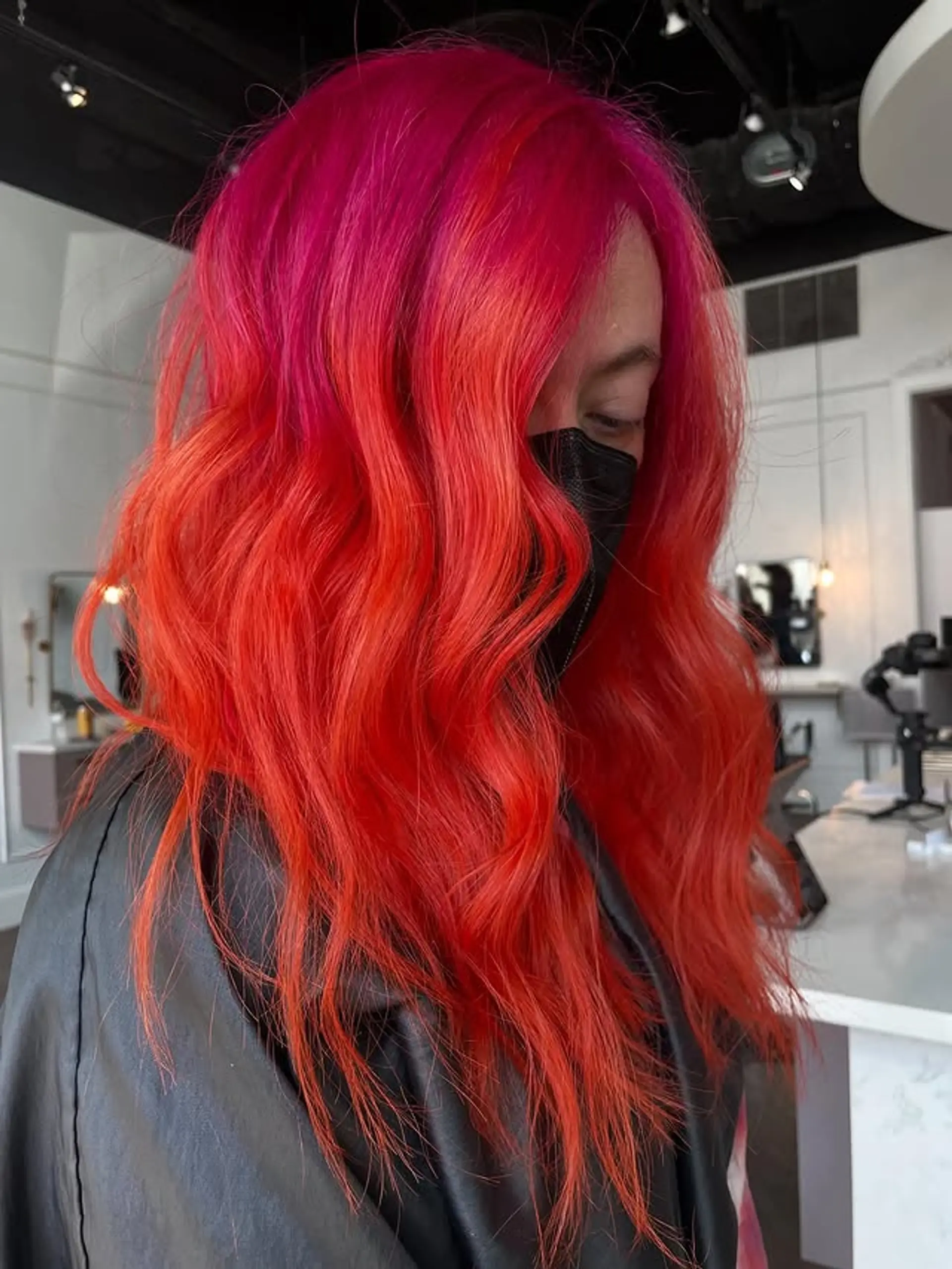 A medium wavy hairstyle with a vibrant ombre effect from pink to fiery orange-red. 1
